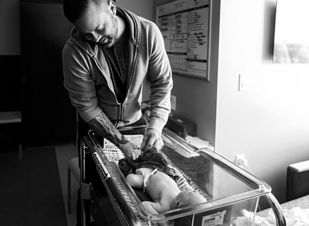 dad dressing baby in the hospital 