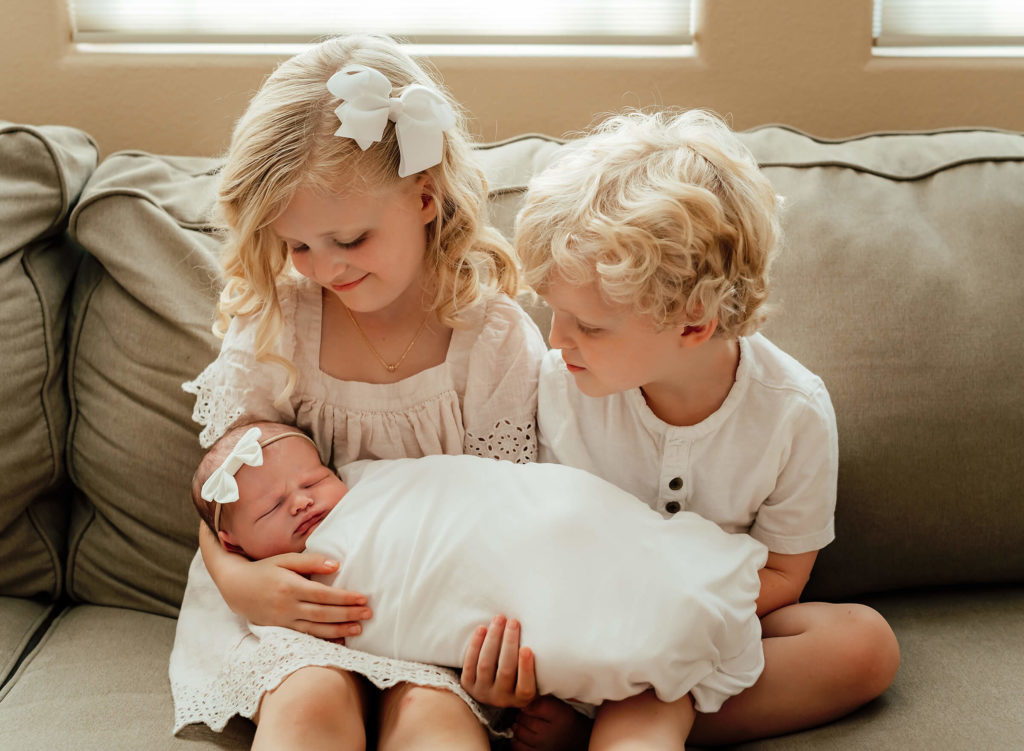 siblings holding their new baby sister during their in home newborn session in Las Vegas