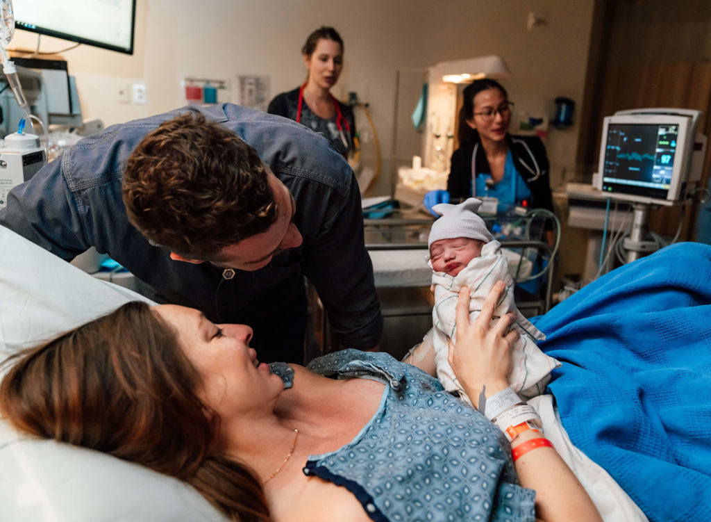 mother and father taking in details of their newborn after delivery