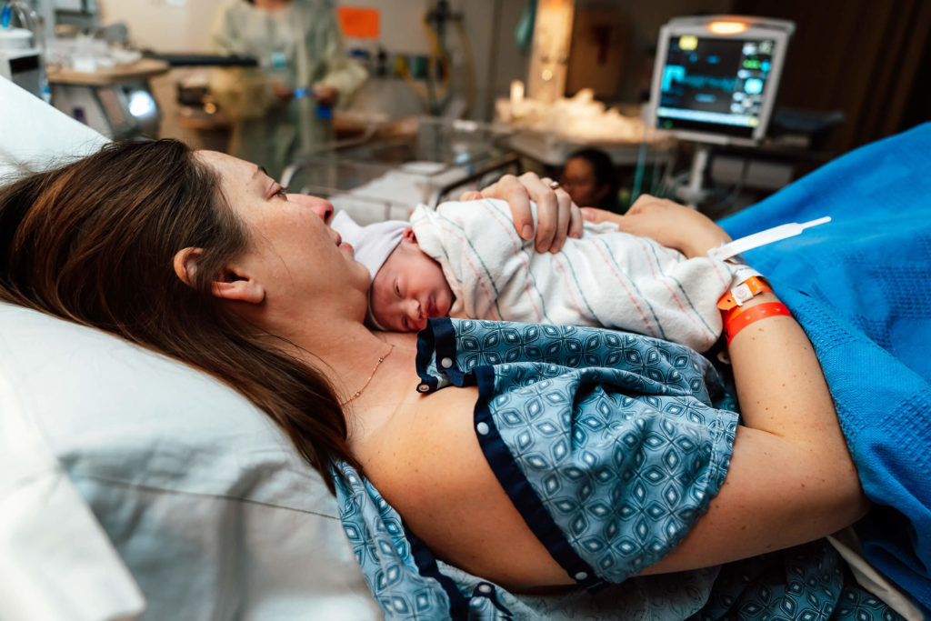 mom holding newborn infant in her arms before being transferred to the nursery