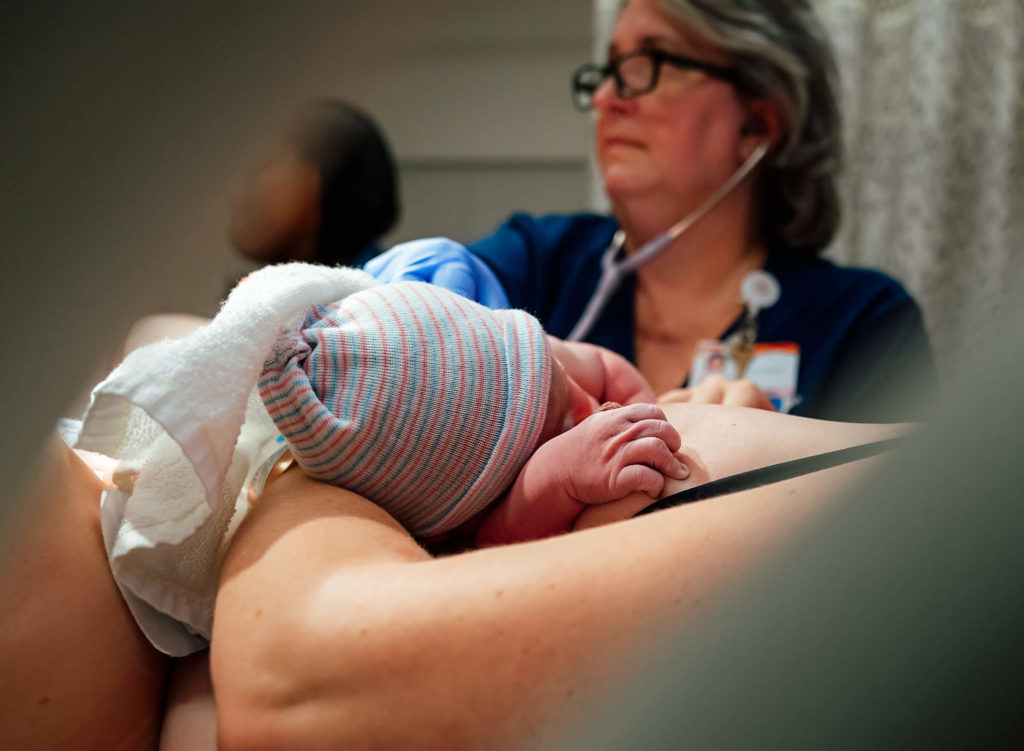 checking vital signs while mother and infant experience skin to skin after a hospital birth 