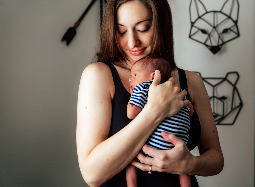 mom holding baby at home during an in-home lifestyle newborn session 
