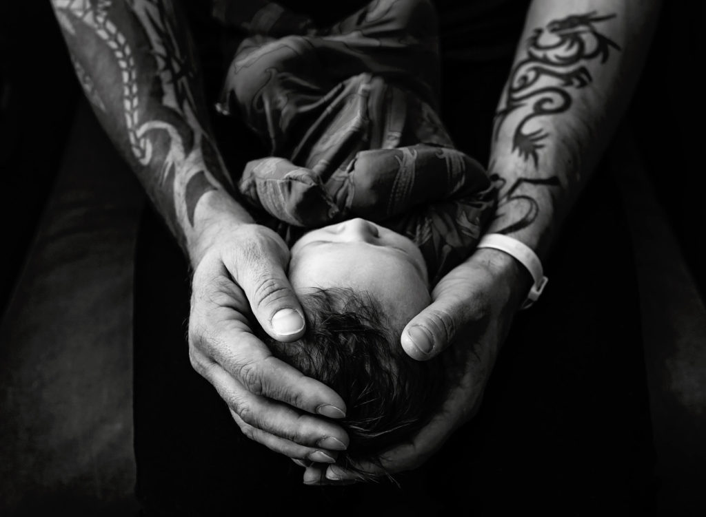 Fresh 48 session using dad's hands holding baby in black and white 