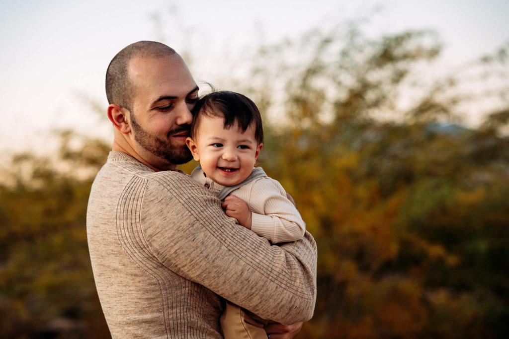 dad holding son during outdoor family session using fall colors in Las Vegas