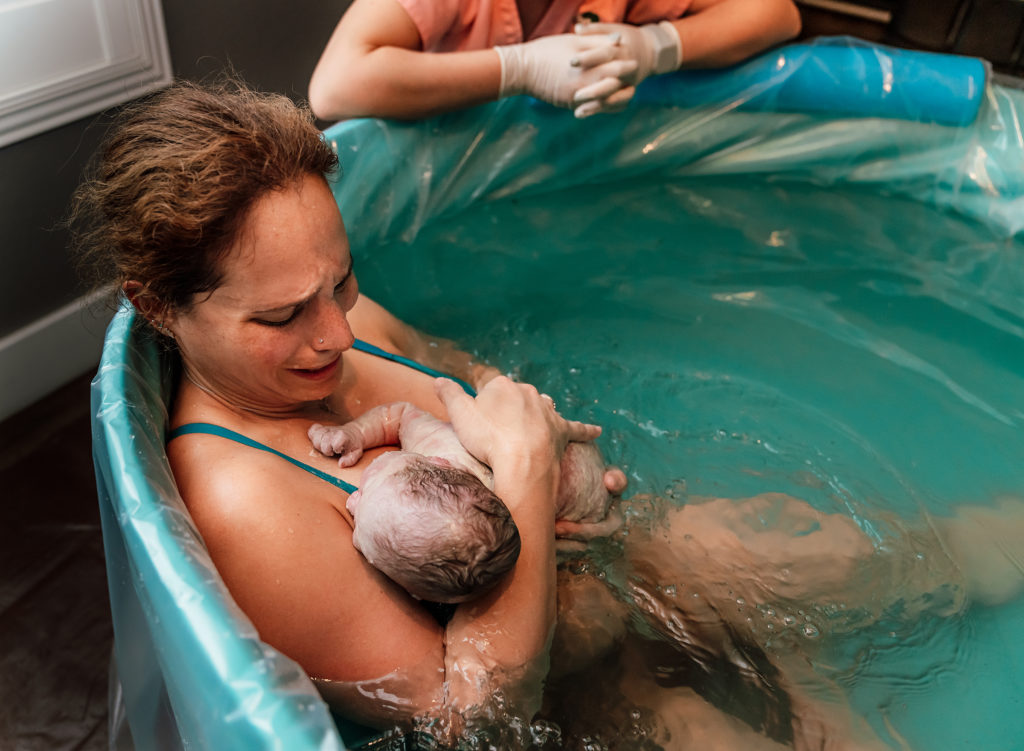 holding baby in your arms after a water birth at home