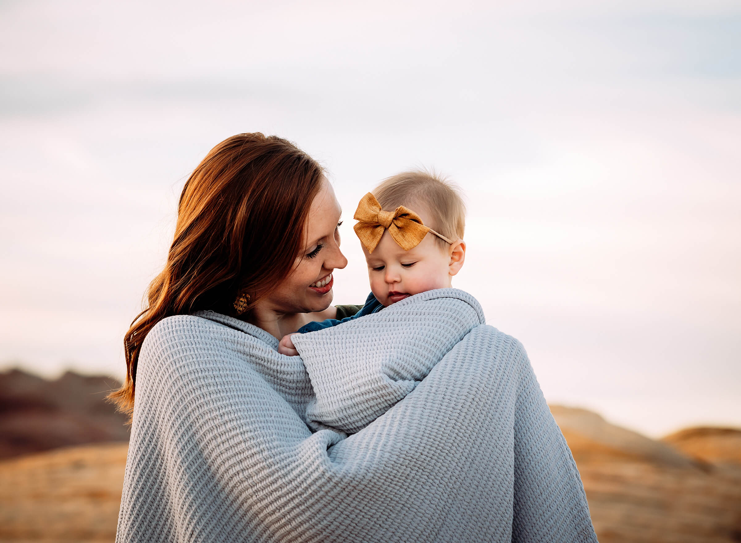 mom holding baby daughter with blanket during a family photography session