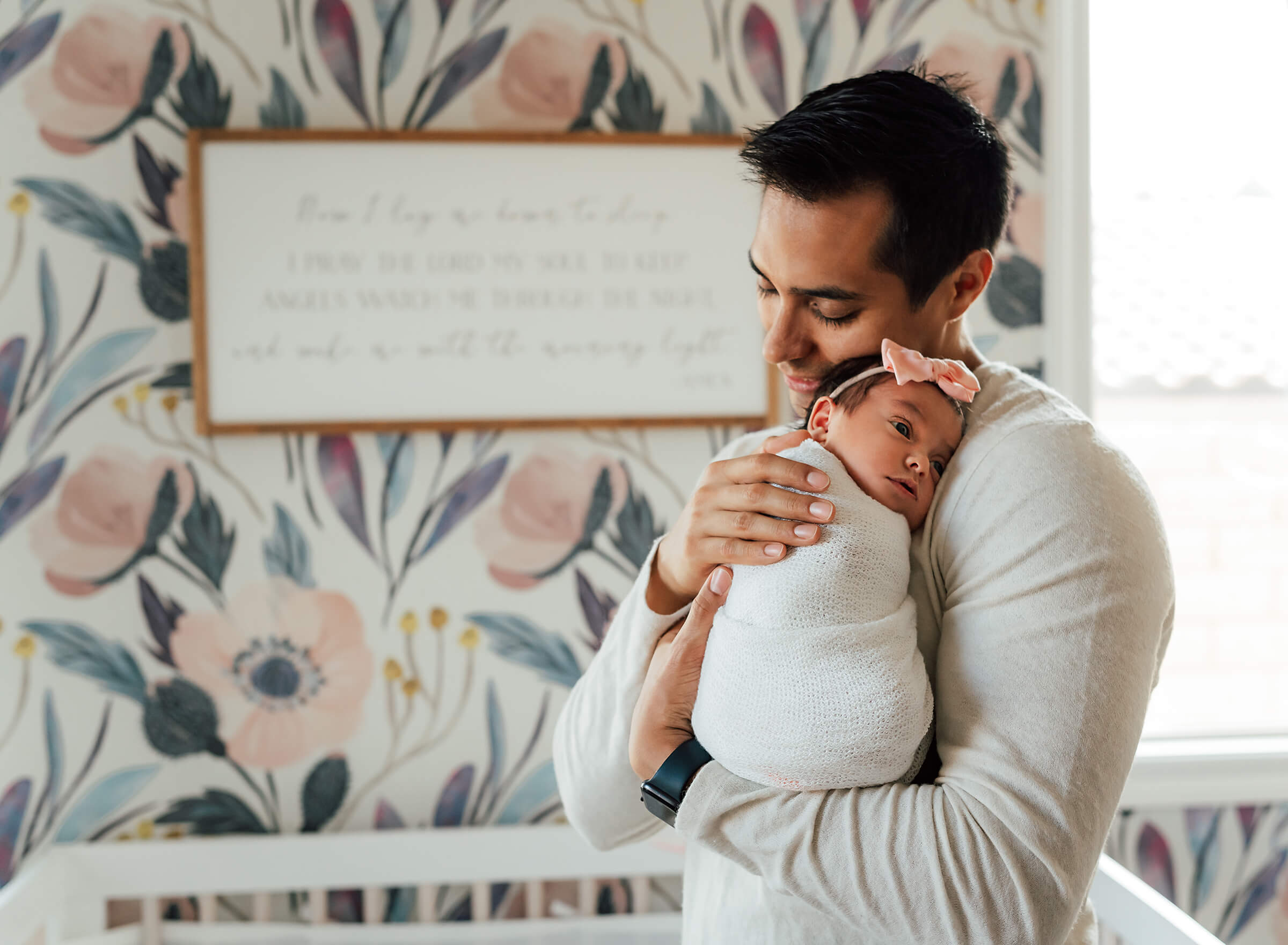 dad tenderly holding new baby girl in his arms during an in home newborn session 