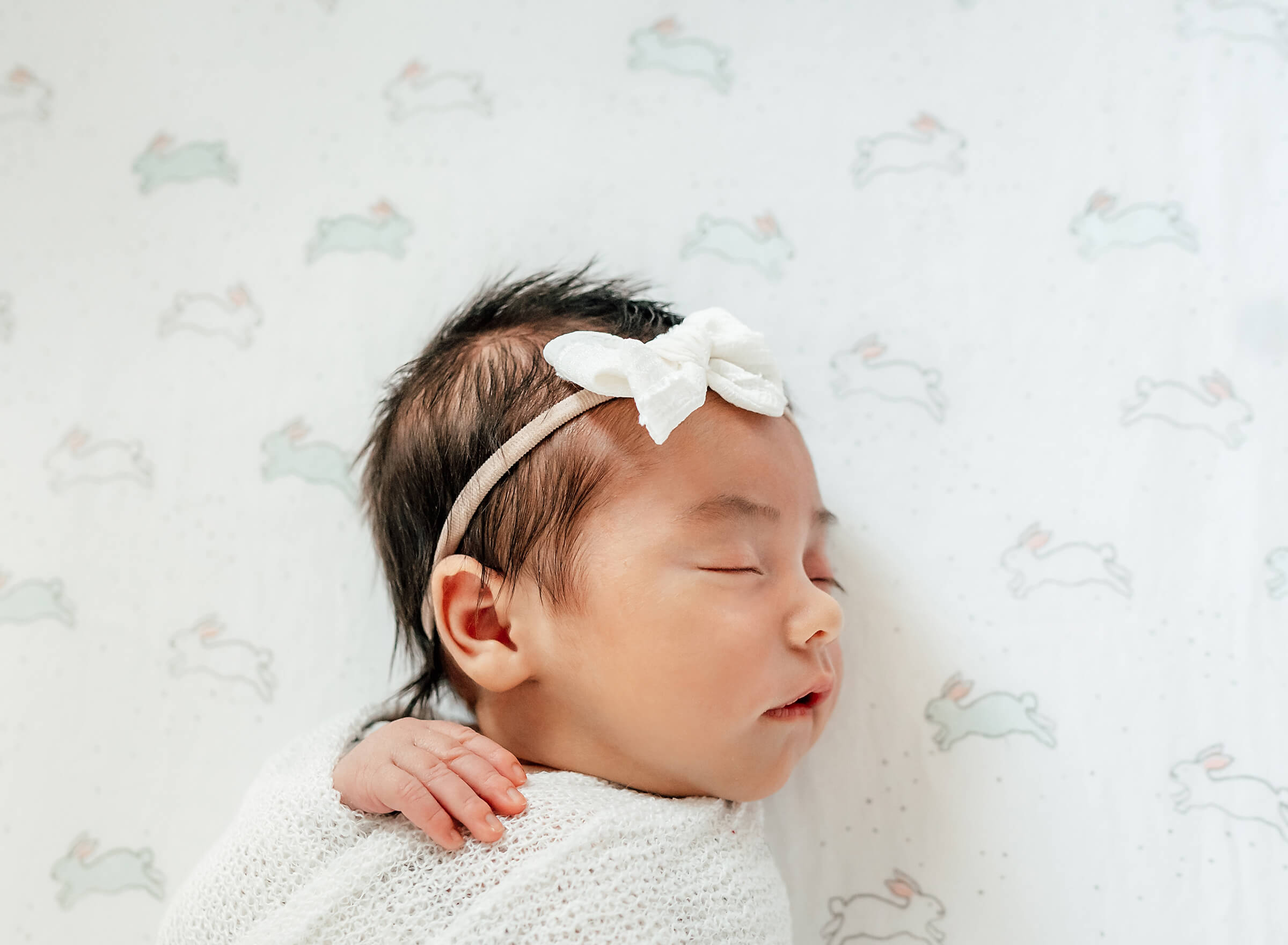 newborn baby girl in her crib during in home lifestyle session 