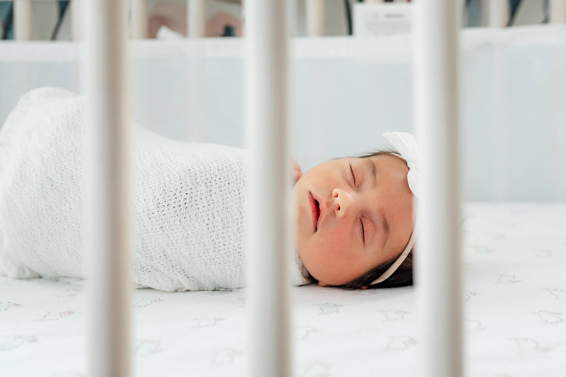 newborn peeking through crib slats during session 
