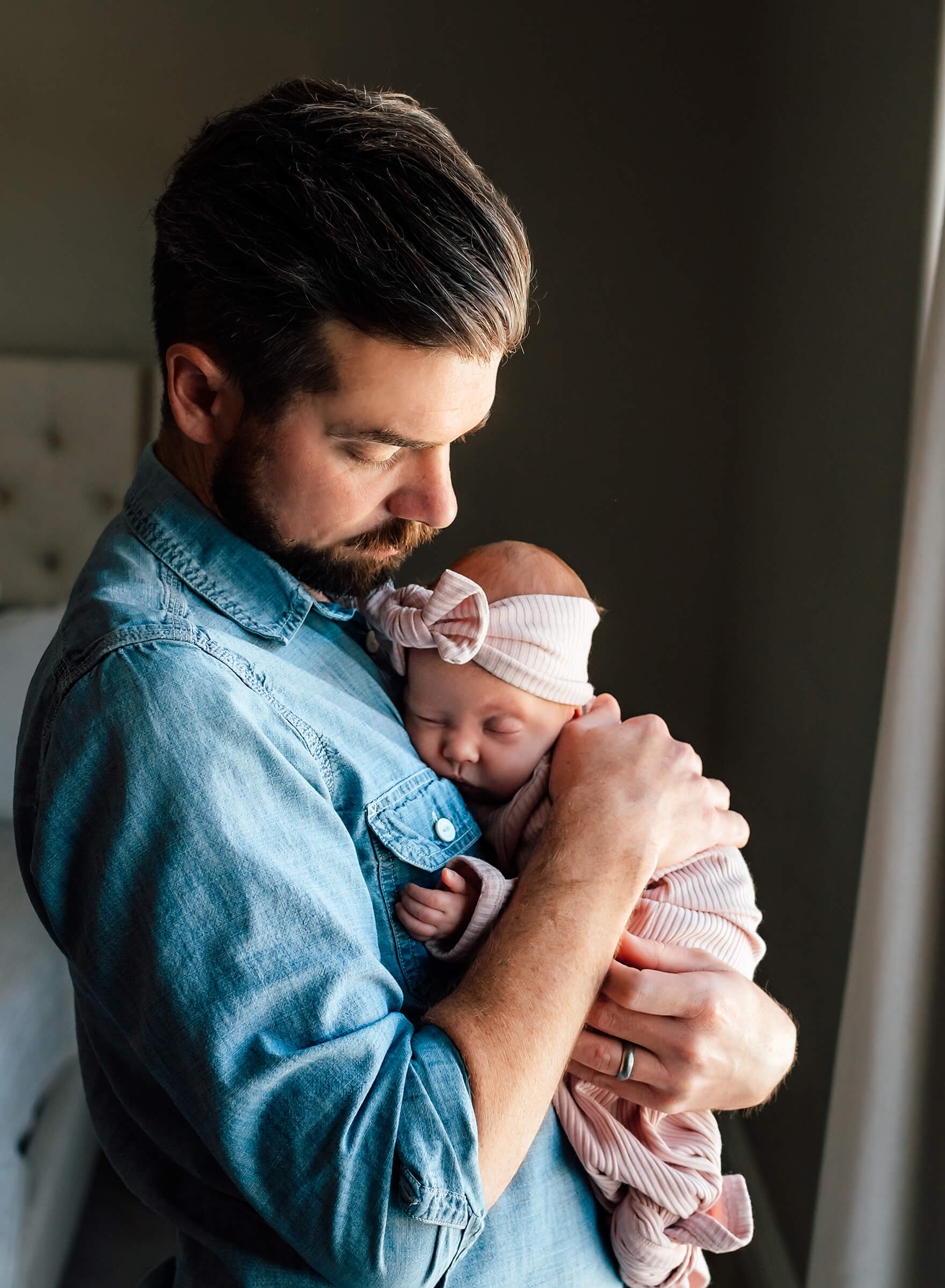 sweet image of a dad holding his newborn baby girl at home 