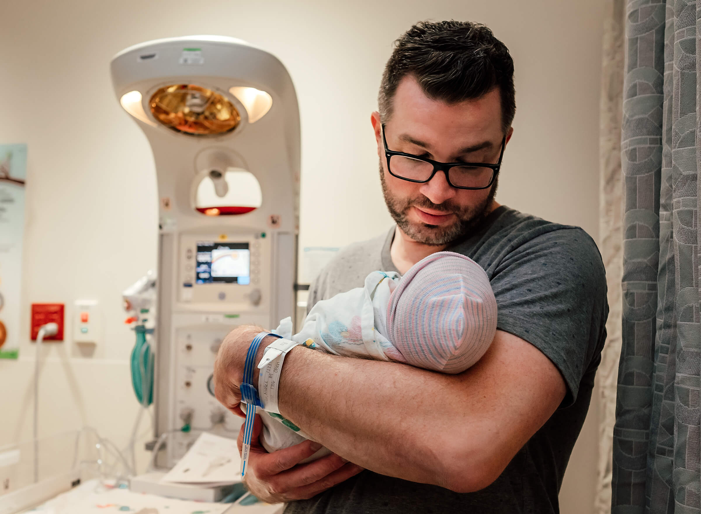 dad holding his son near the radiant warmer after a hospital birth in Las Vegas