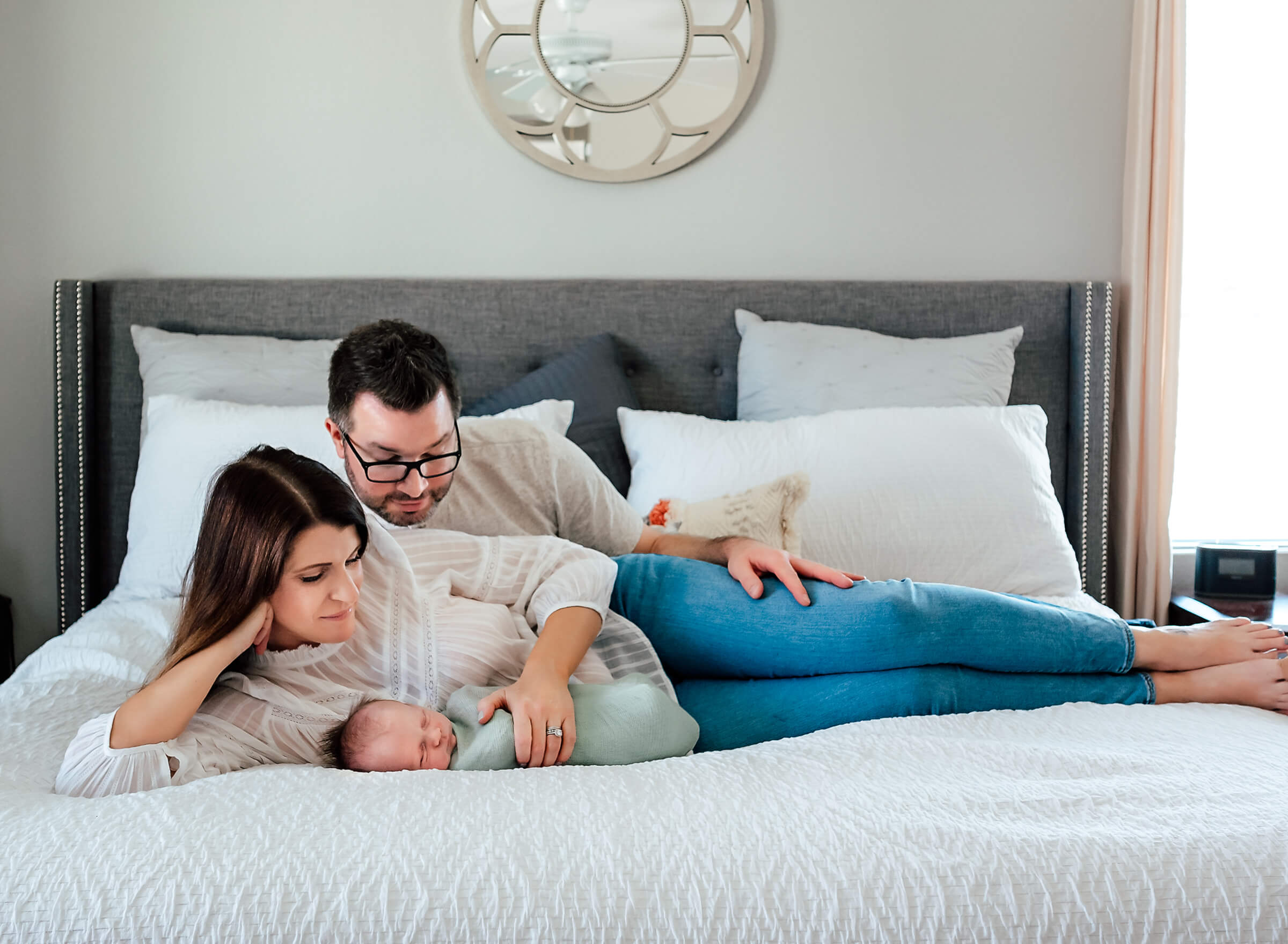 mom dad and baby on bed at home during newborn session 