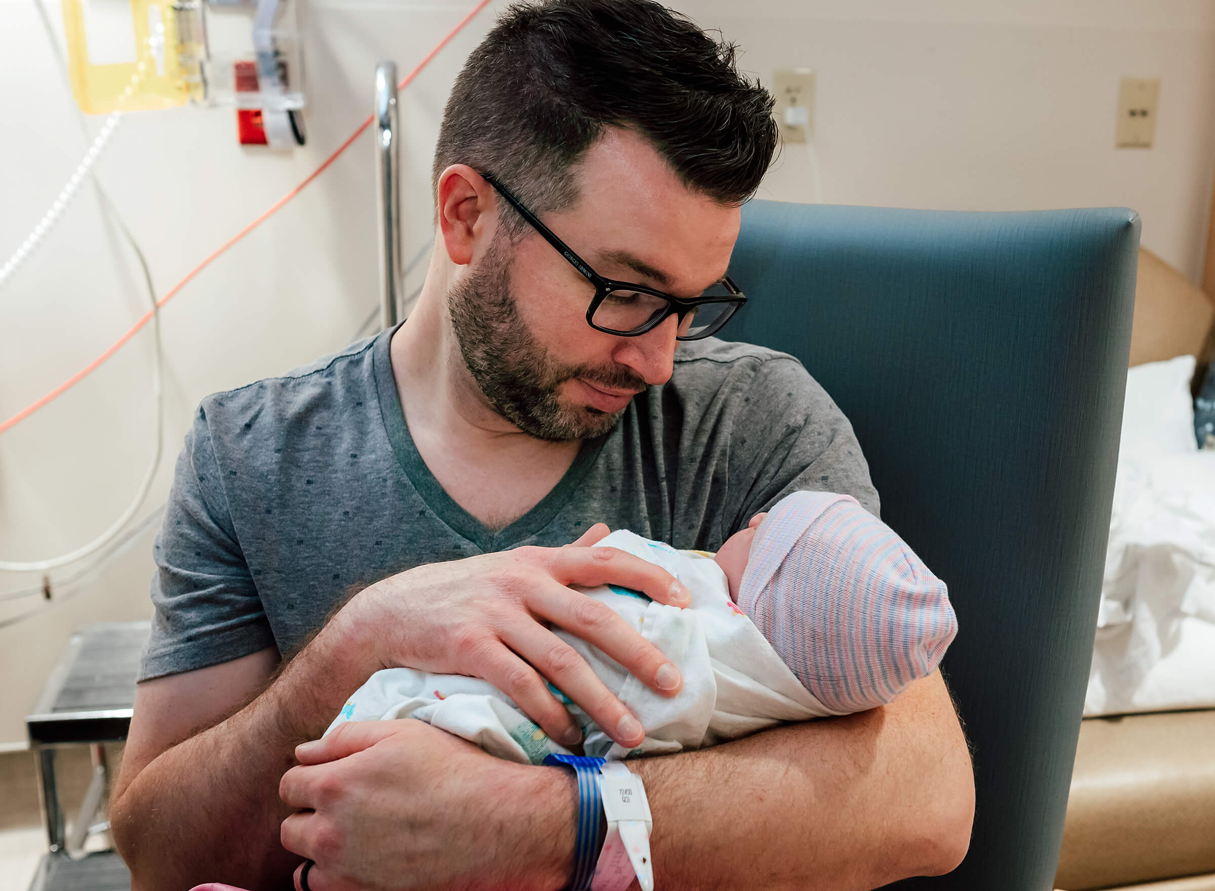 dad holding his son after birth while mother rests 