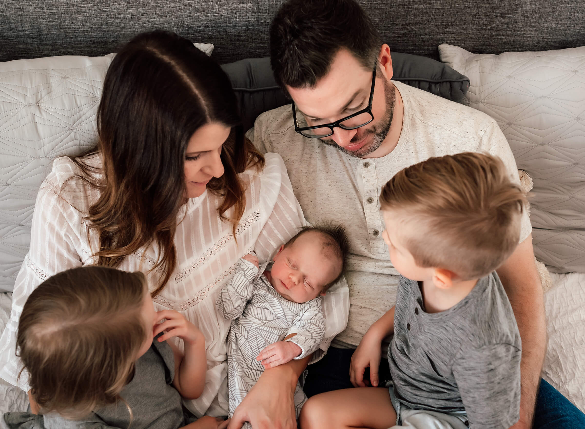whole family together on the parents bed during in home newborn session 