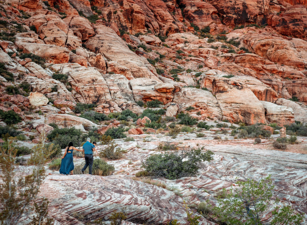 family walking together in a wide angle image of the beautiful red rocks surrounding las vegas