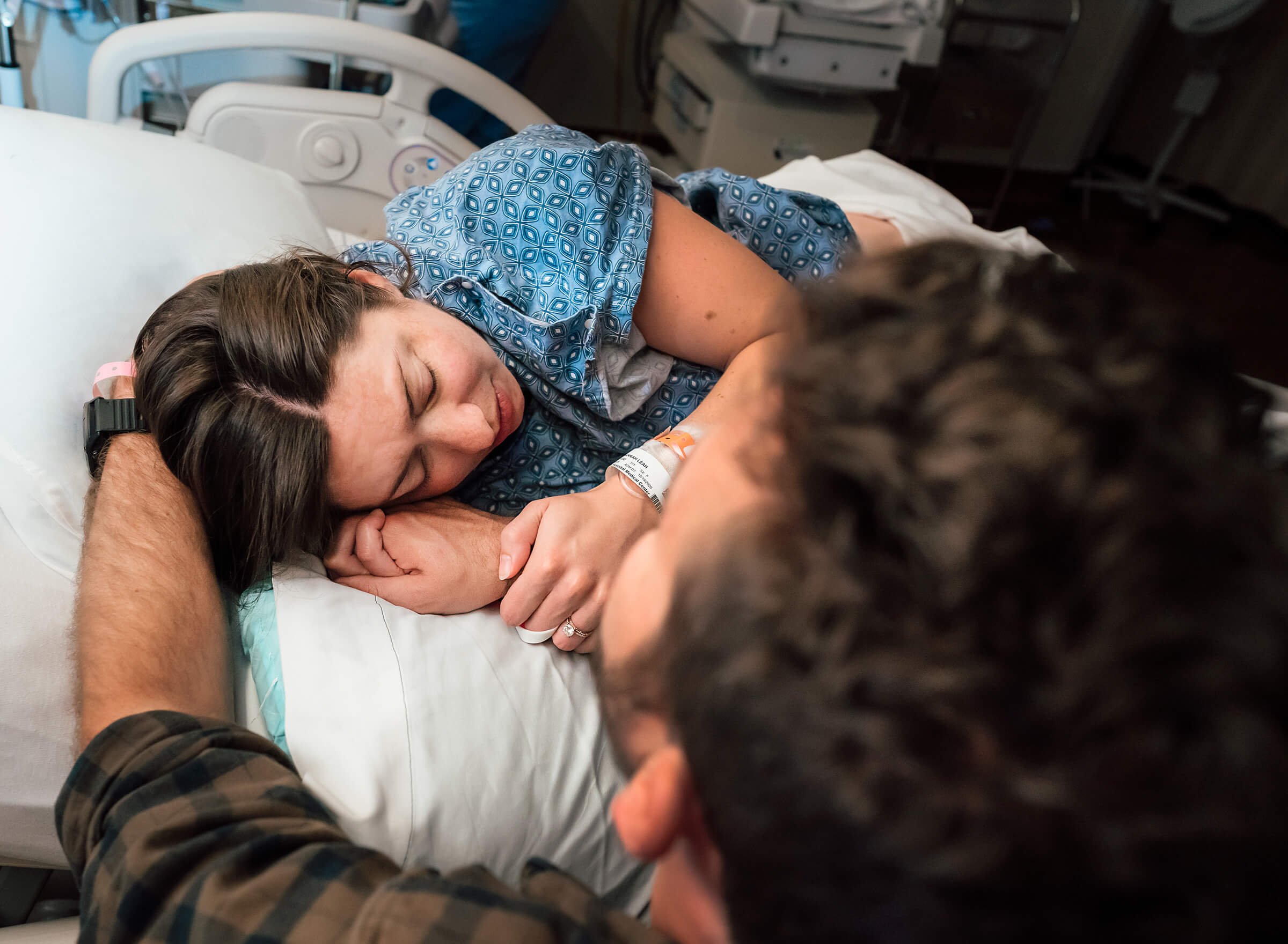 husband staying by his wife's bedside as she labors in the hospital
