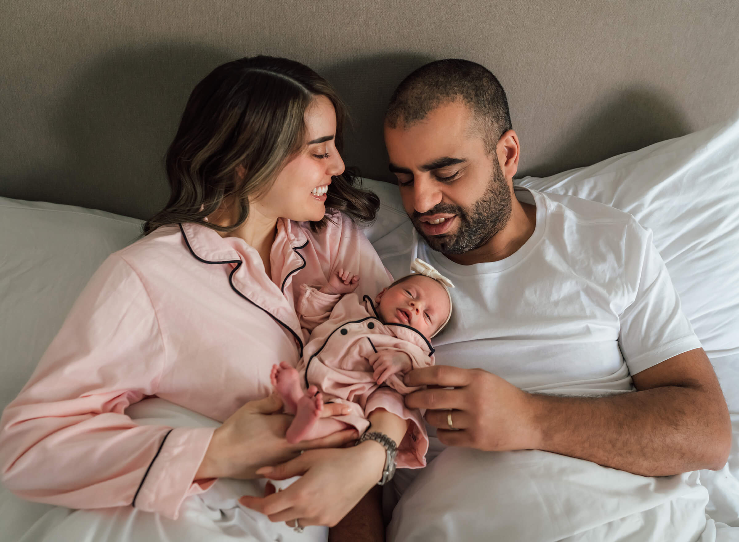 mom and dad holding daughter during newborn session at home. 