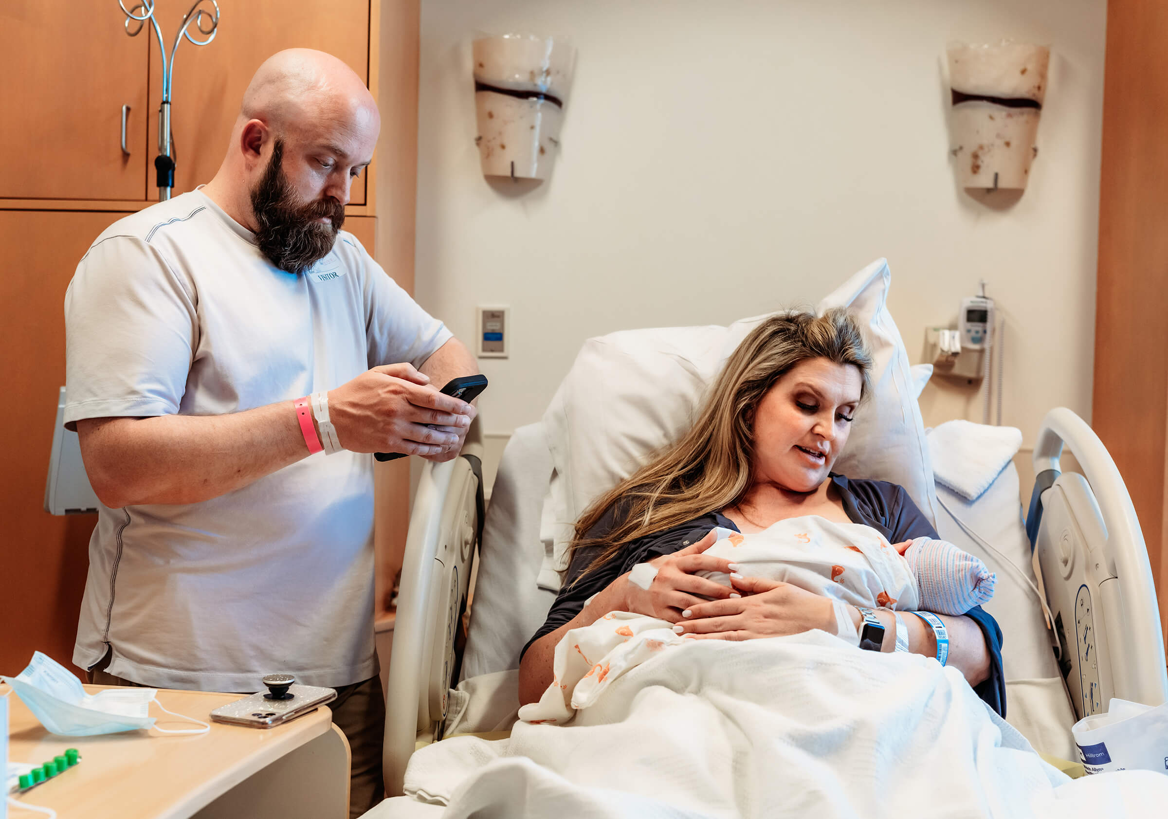 husband texting family after the birth of their baby