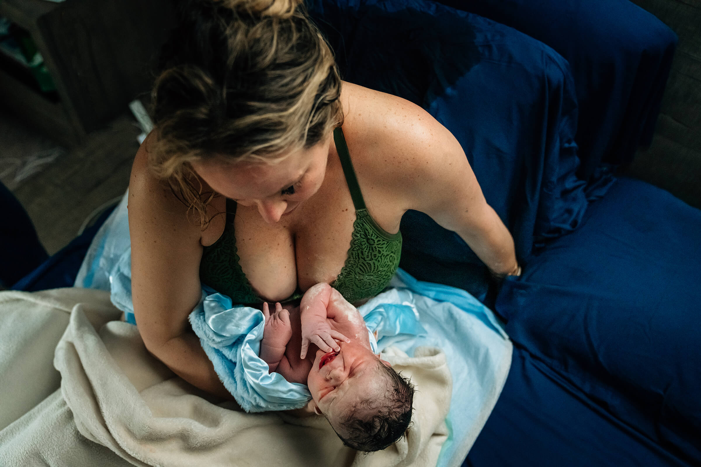 mother in bed looking at her new son just moments after delivery