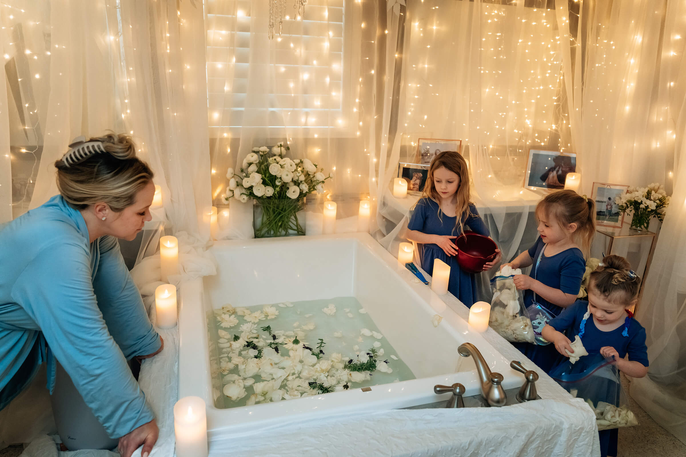 daughters filling tub with flower petals as their mother labors at home