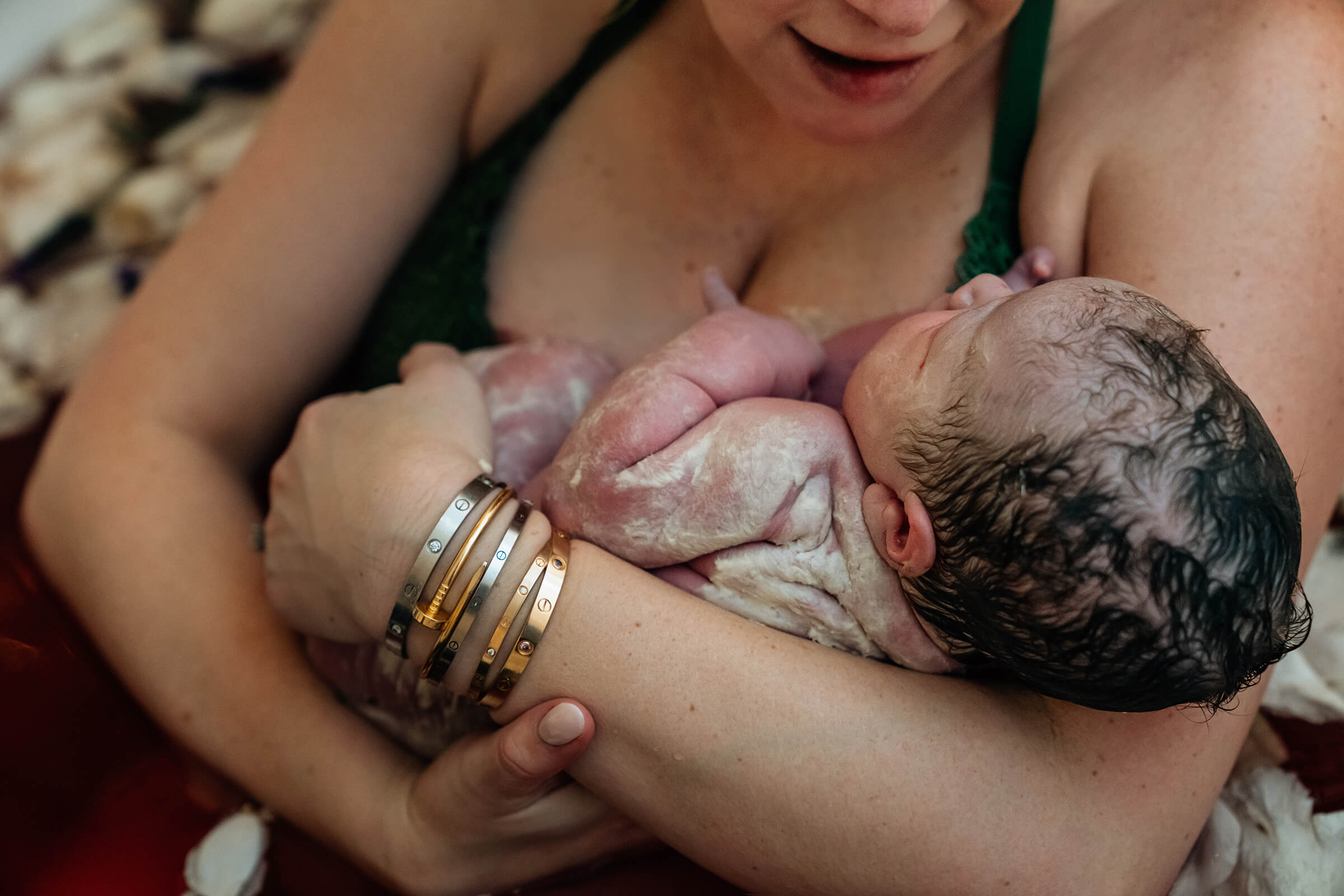 newborn in his mother's arms covered in vernix right after delivery 