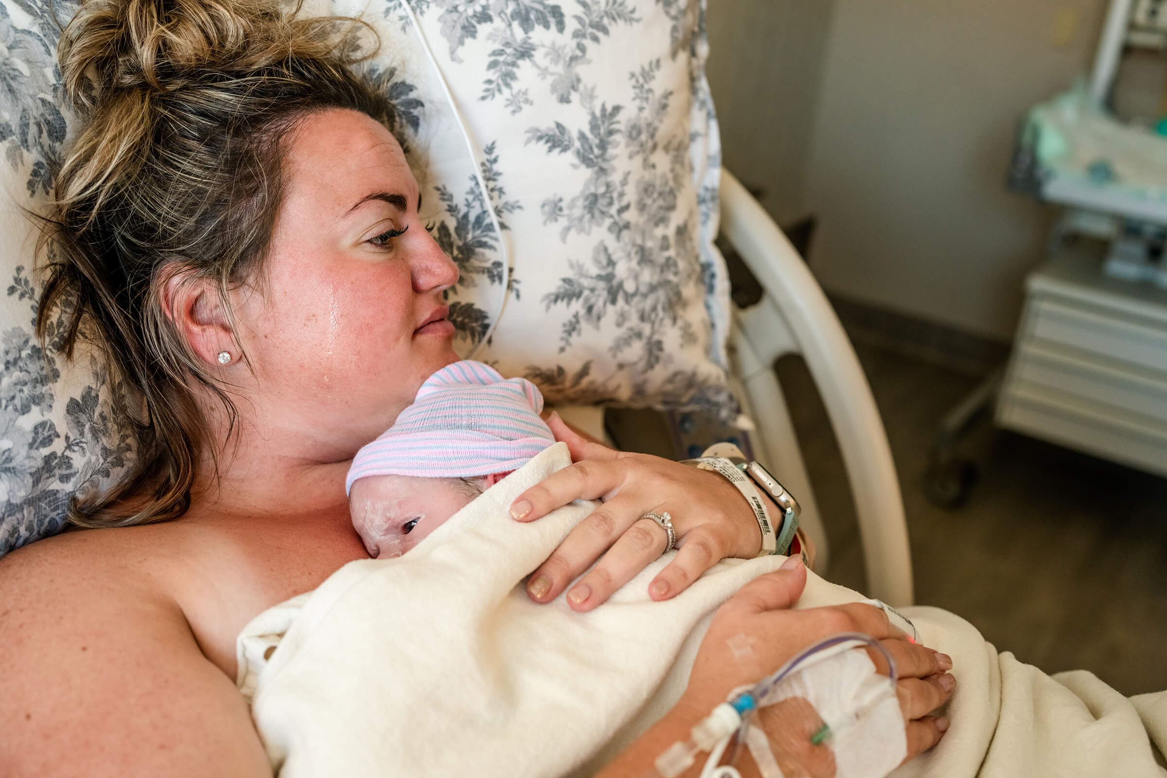 a mother crying as she holds her newborn daughter after years of struggling through IVF
