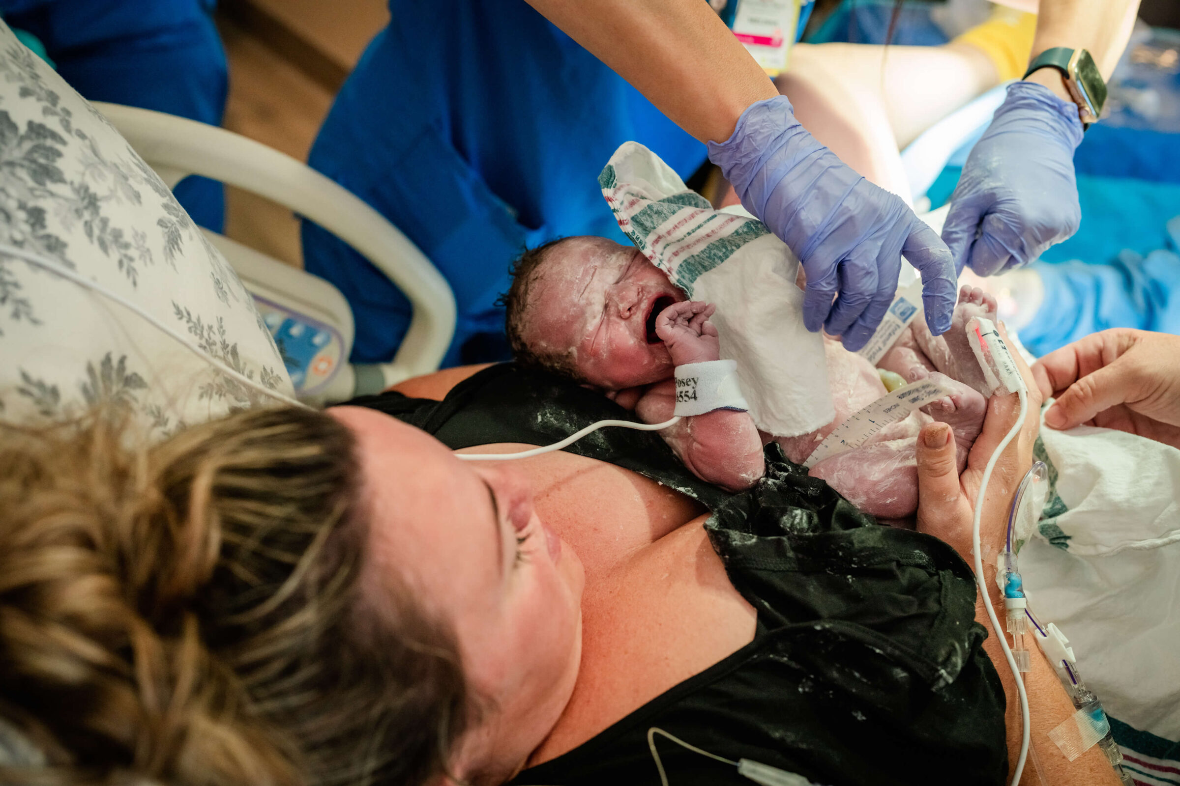 nursery nurse drying off baby with a towel after delivery in a hospital