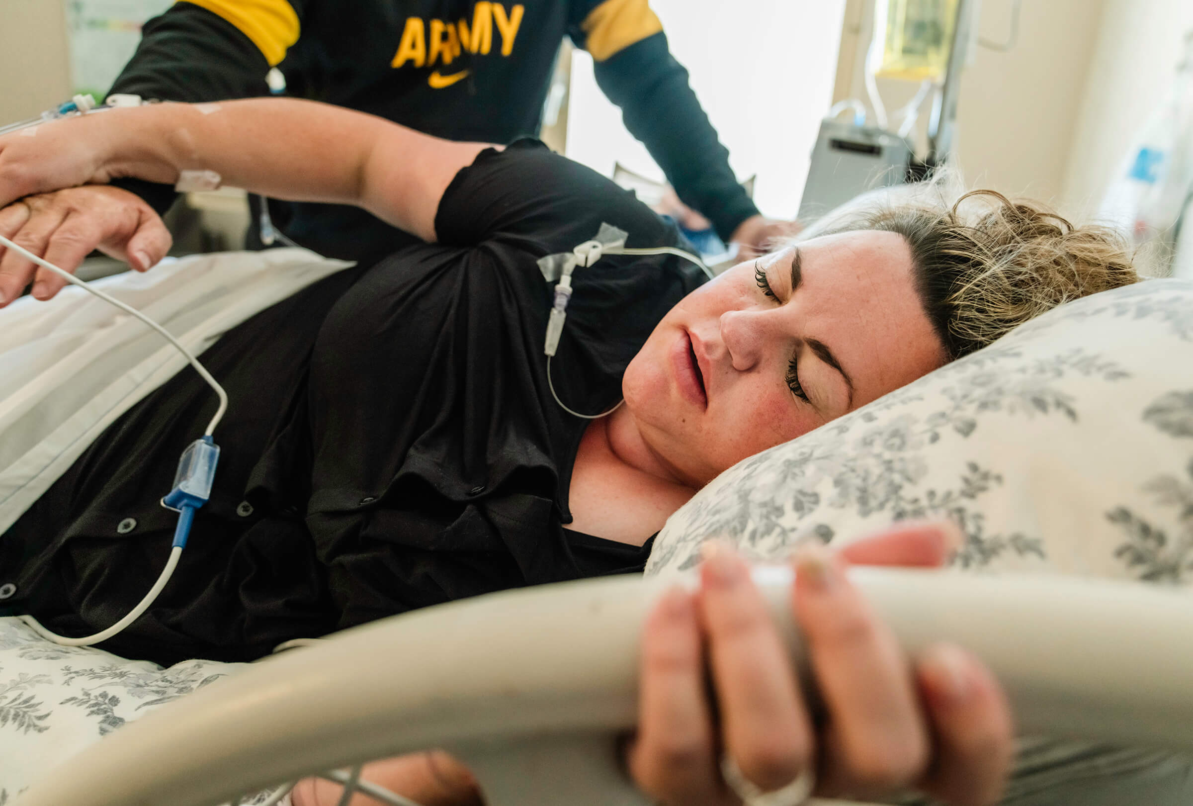 mother grasping bedrail as she breathes a contraction while in a hospital bed.