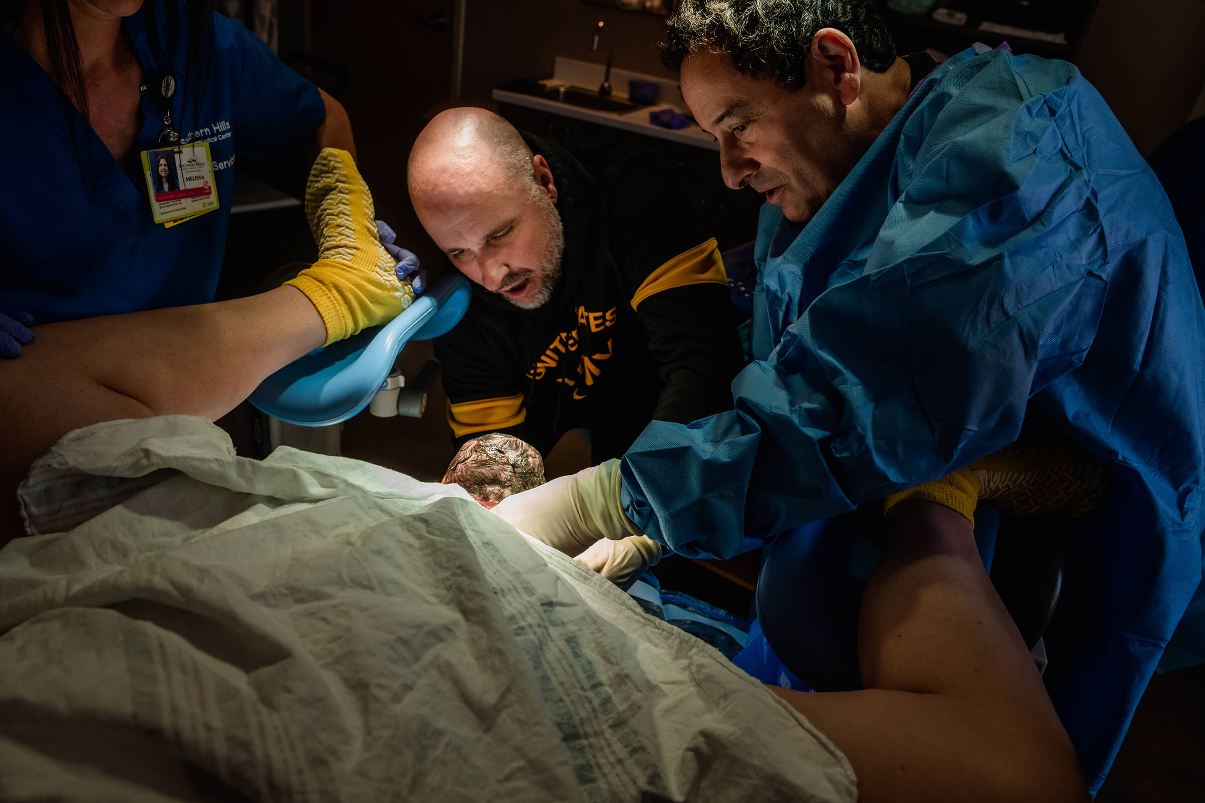 father helping doctor deliver his daughter in the hospital