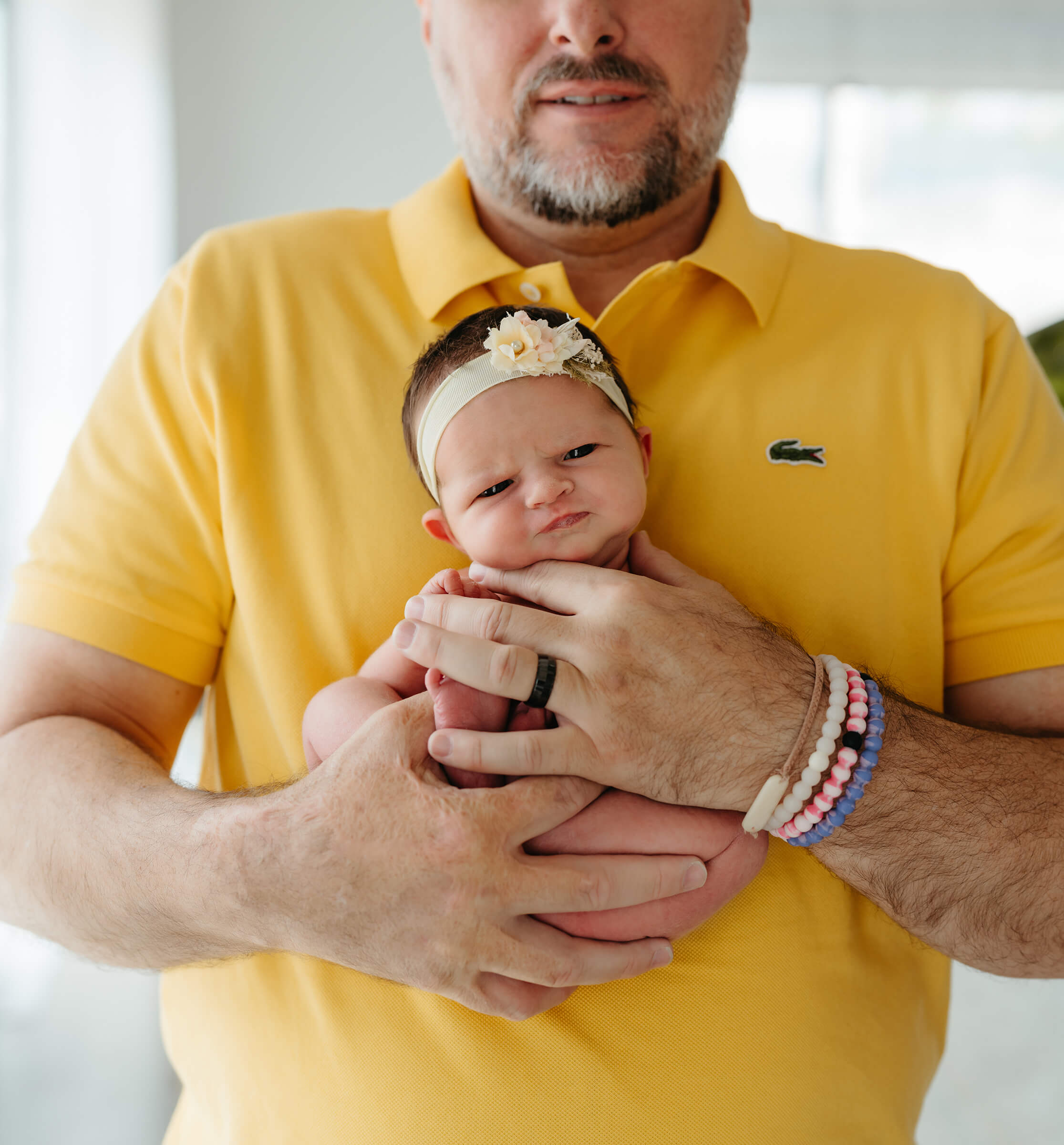 father holding his daughter in his arms while supporting her head during a posed newborn session 