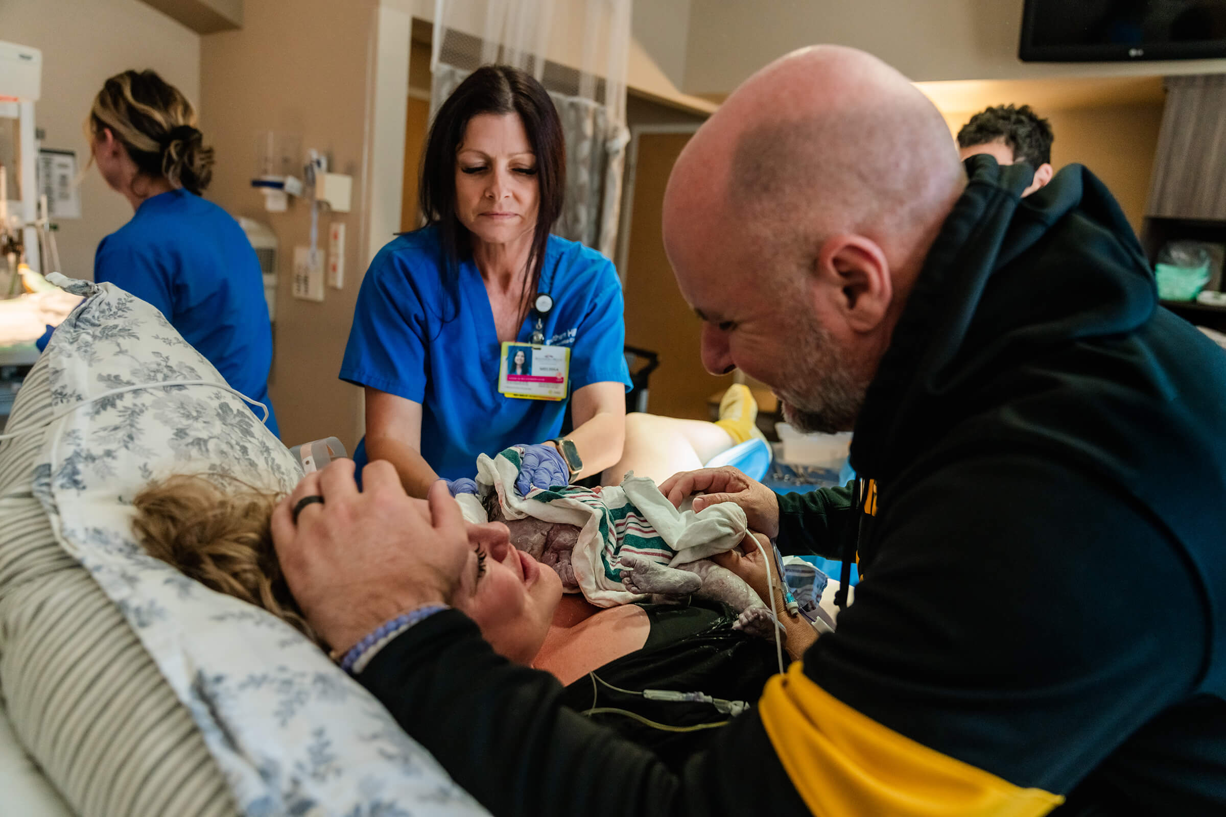 husband looking in his wife's eyes after she delivers their baby