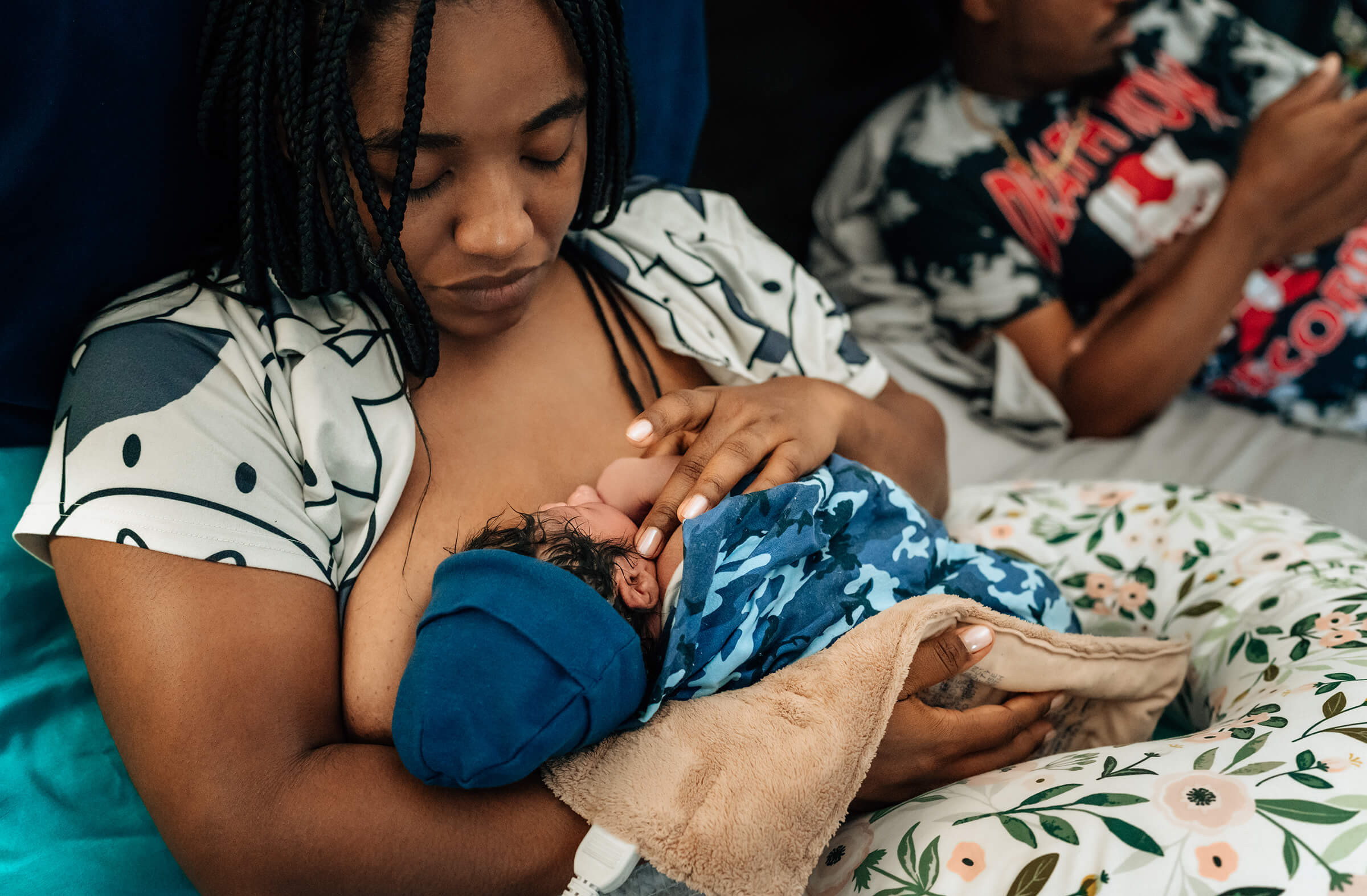 a mother taking all of her newborn baby's details as she holds him in her arms.