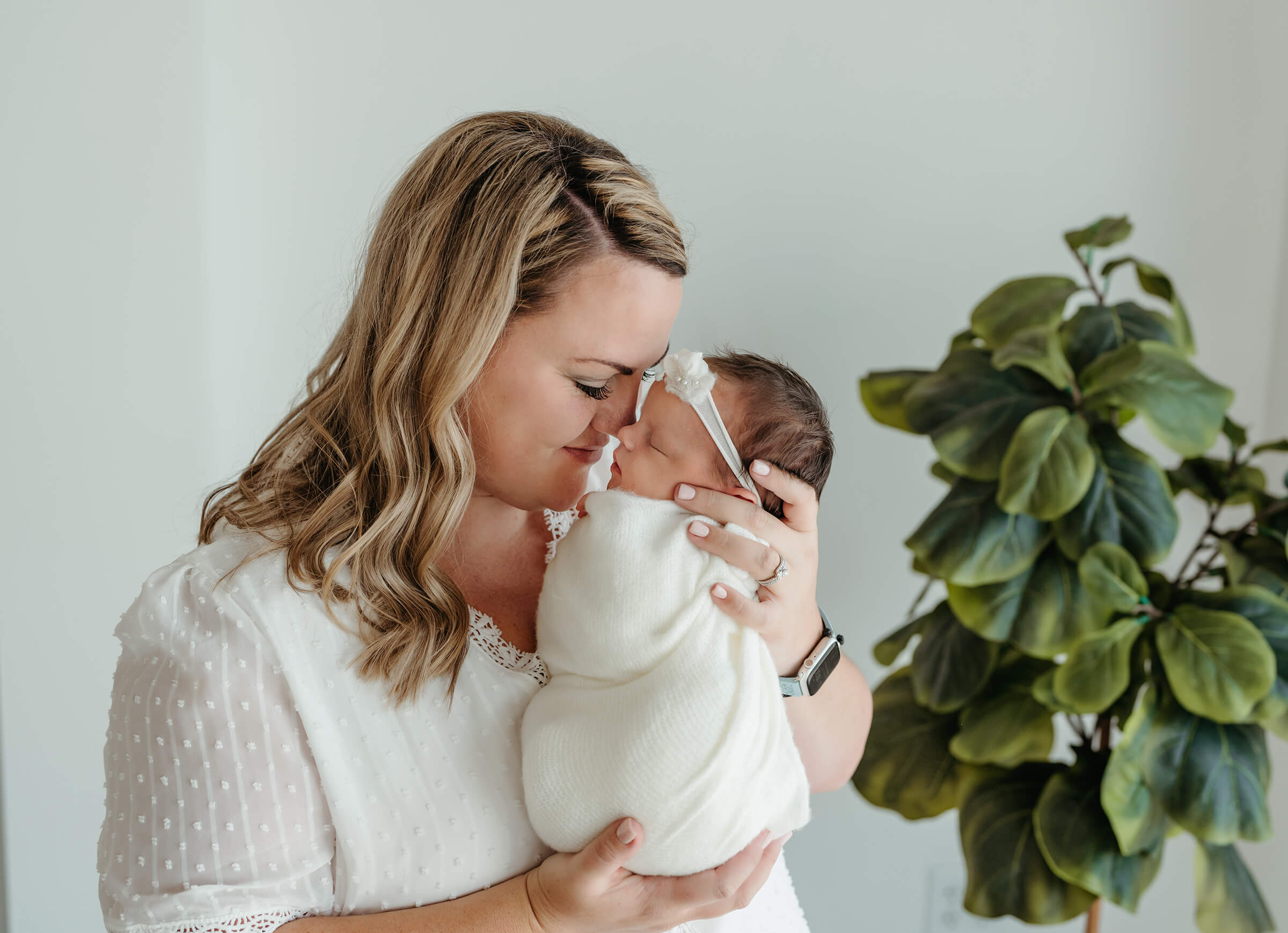 mother holding her newborn daughter hose to nose in a newborn session