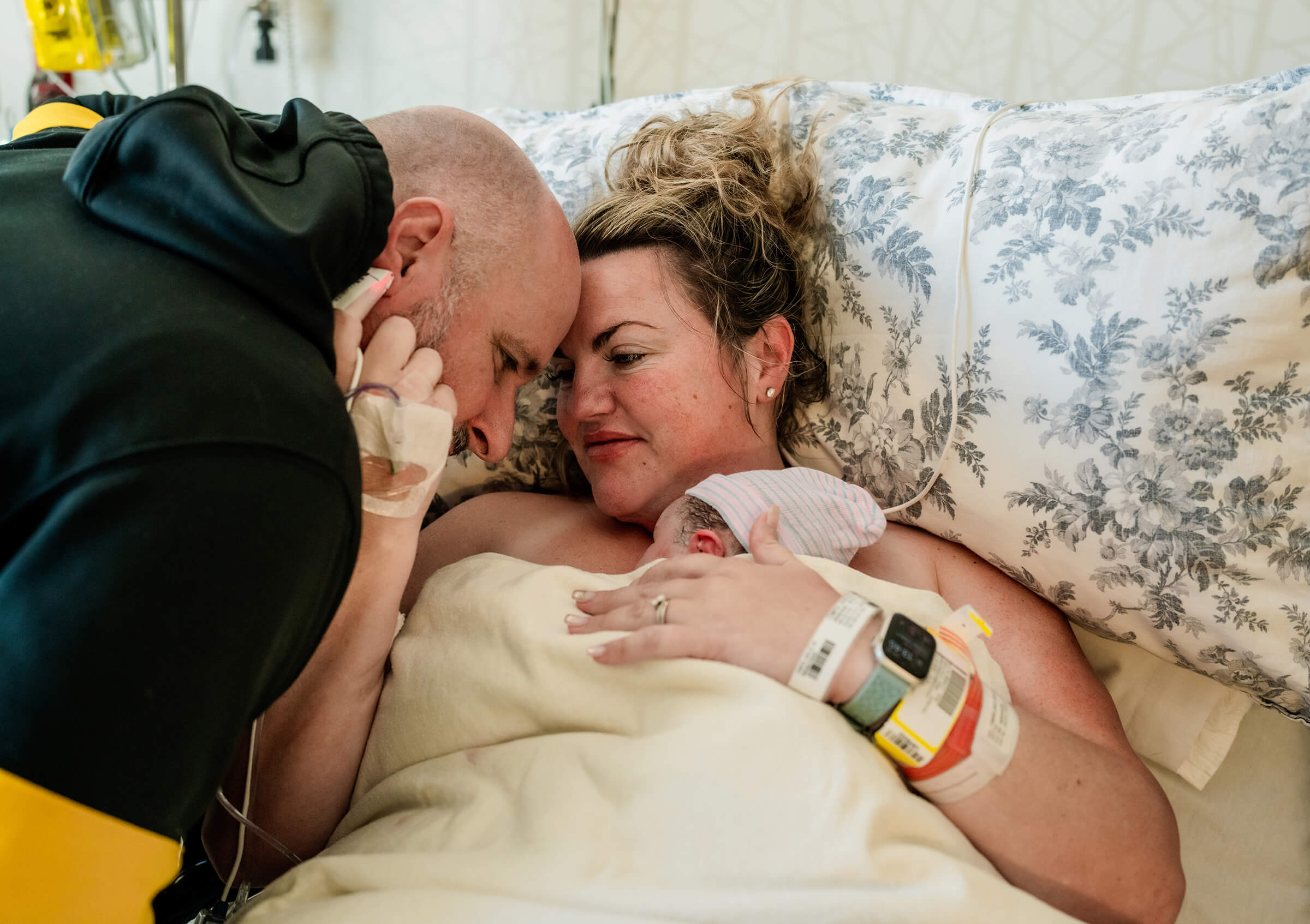 husband and wife touching forheads together in a tender moment after the delivery of their baby