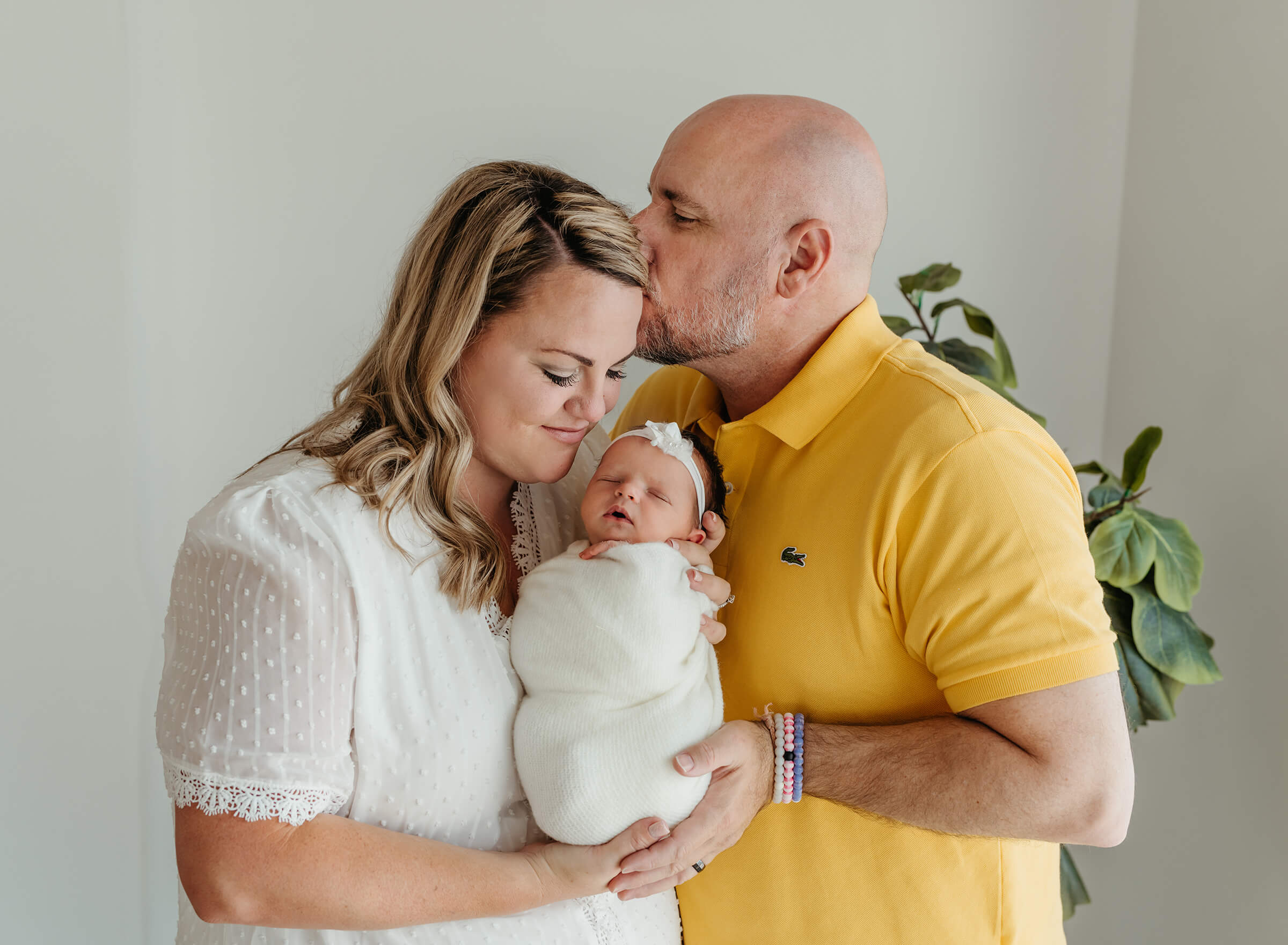 parents holding their newborn swaddled in white during a studio newborn session