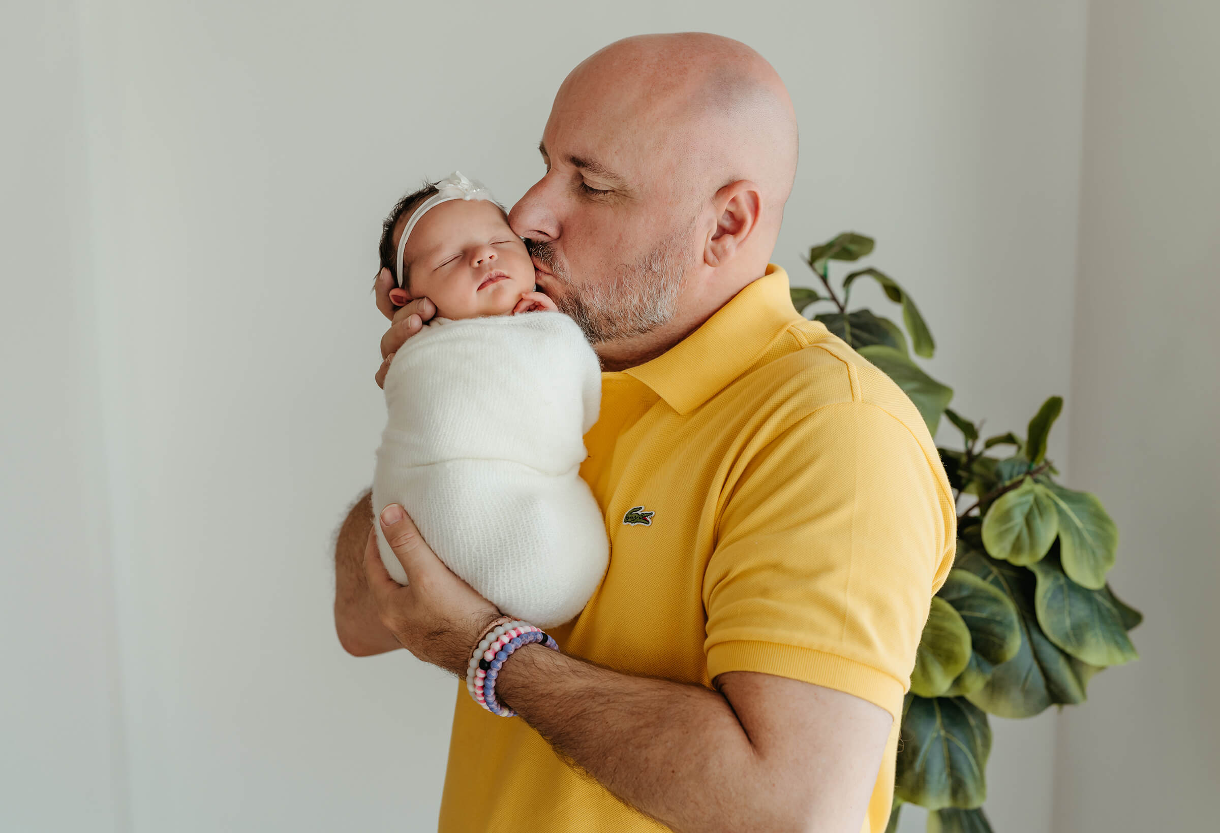 father kissing his newborn daughter during newborn session 