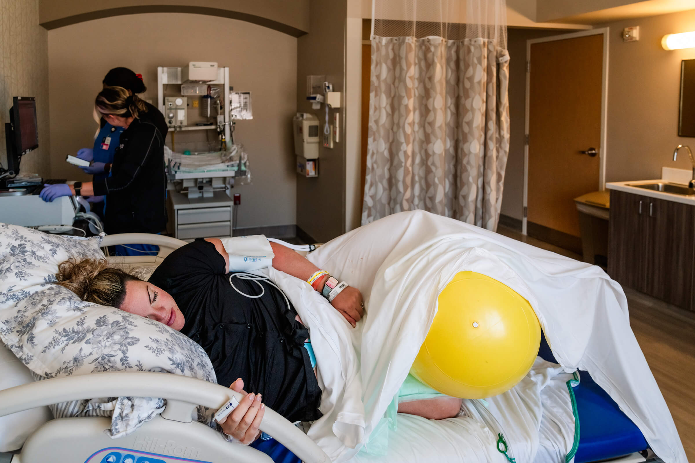 a person lying in a hospital bed with a yellow ball while in labor