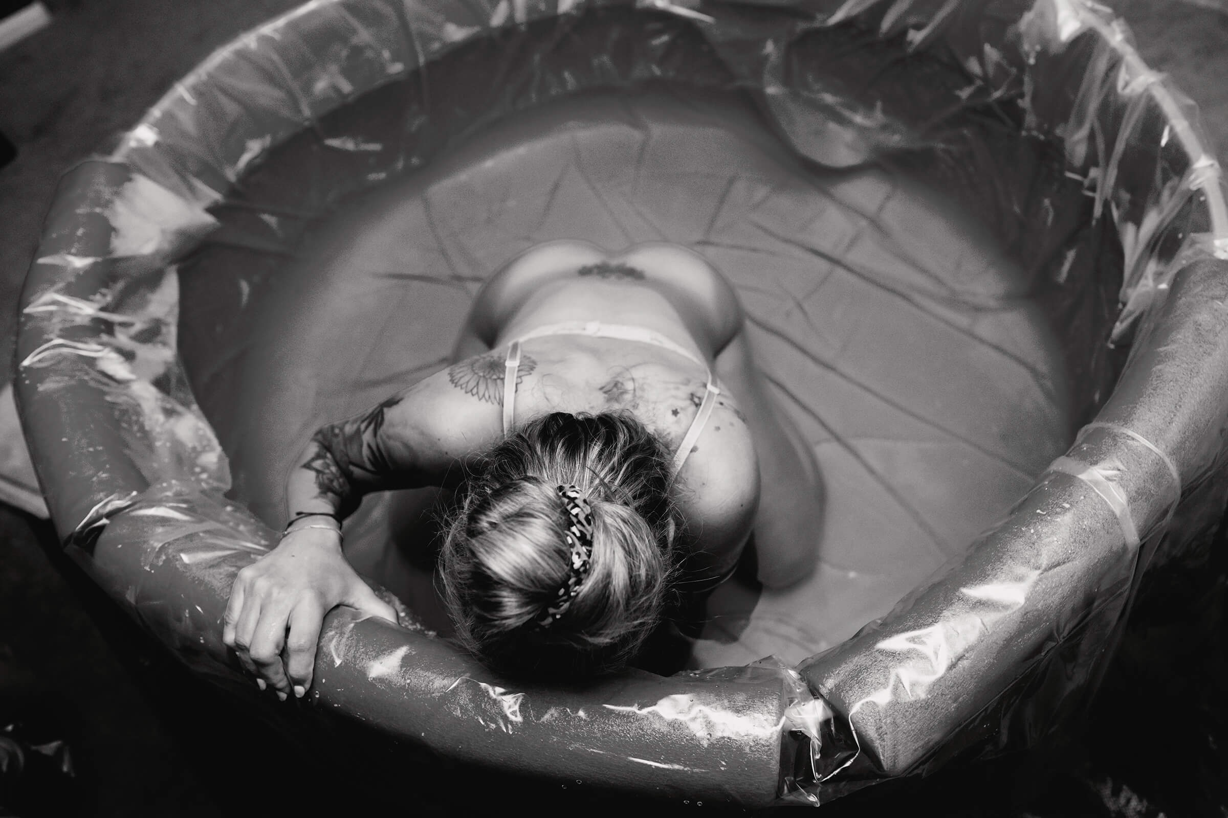 black and white image of a woman leaning forward in water during a home birth in Las Vegas