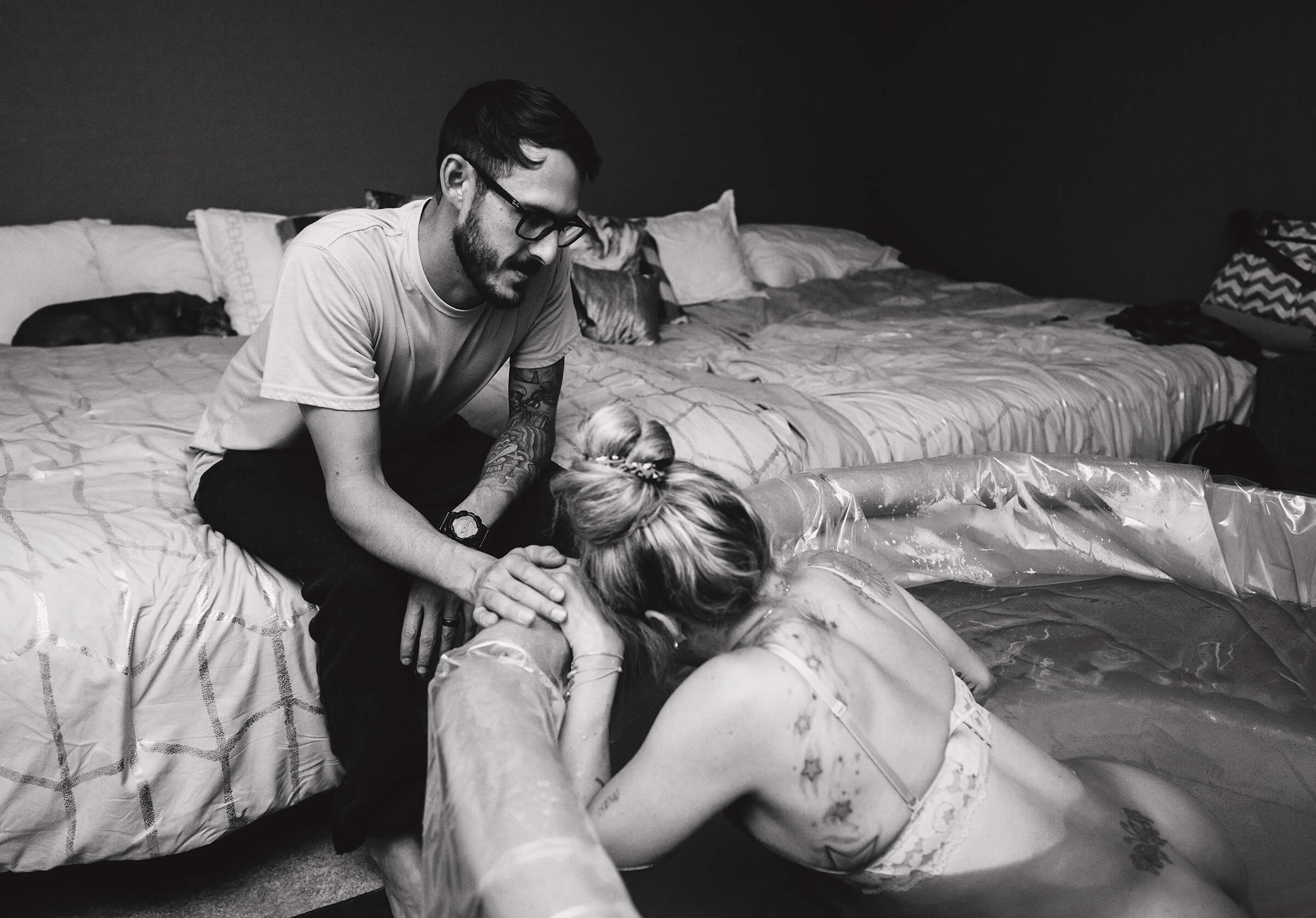 husband touching his wife's hand as she labors in the water at home