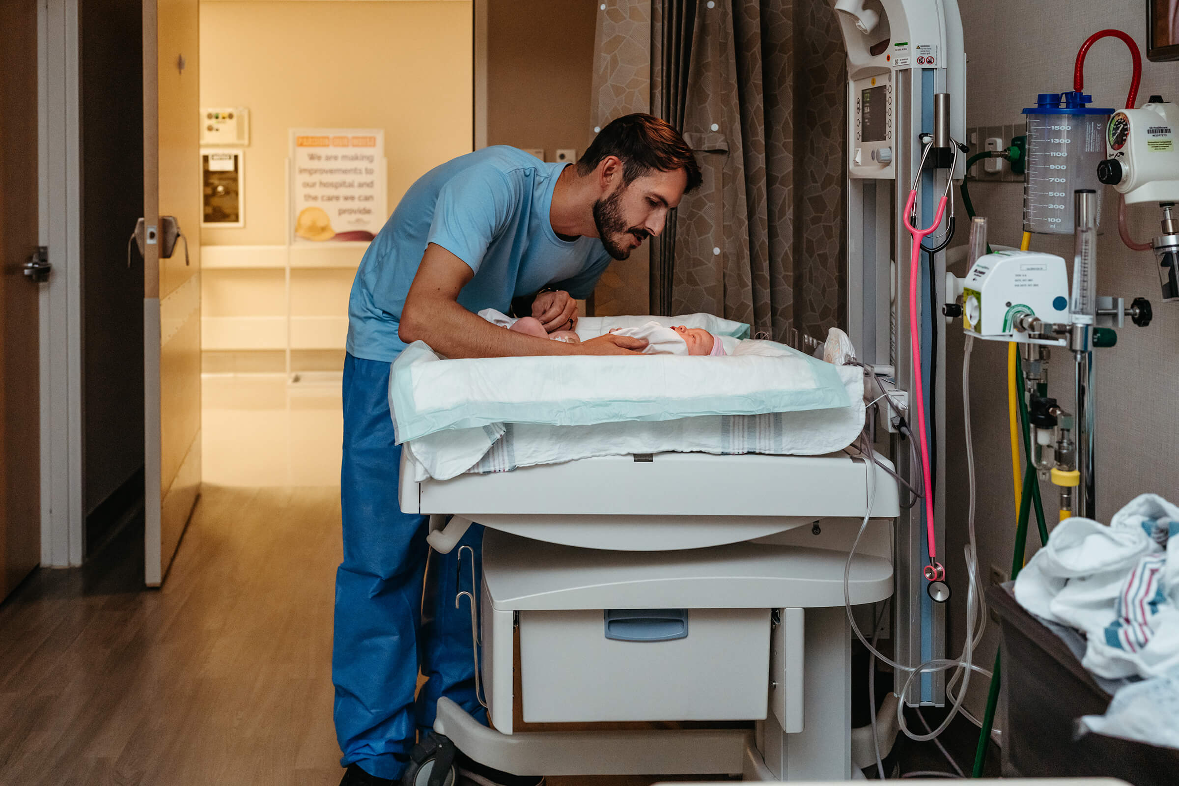 father staying at his baby's side while under the radiant warmer