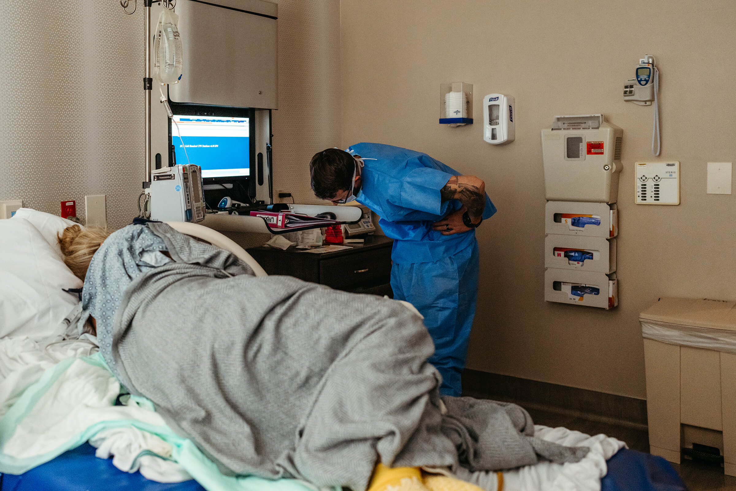 father looking at fetal monitoring tracing in the hospital while wife is being prepped for a cesarean