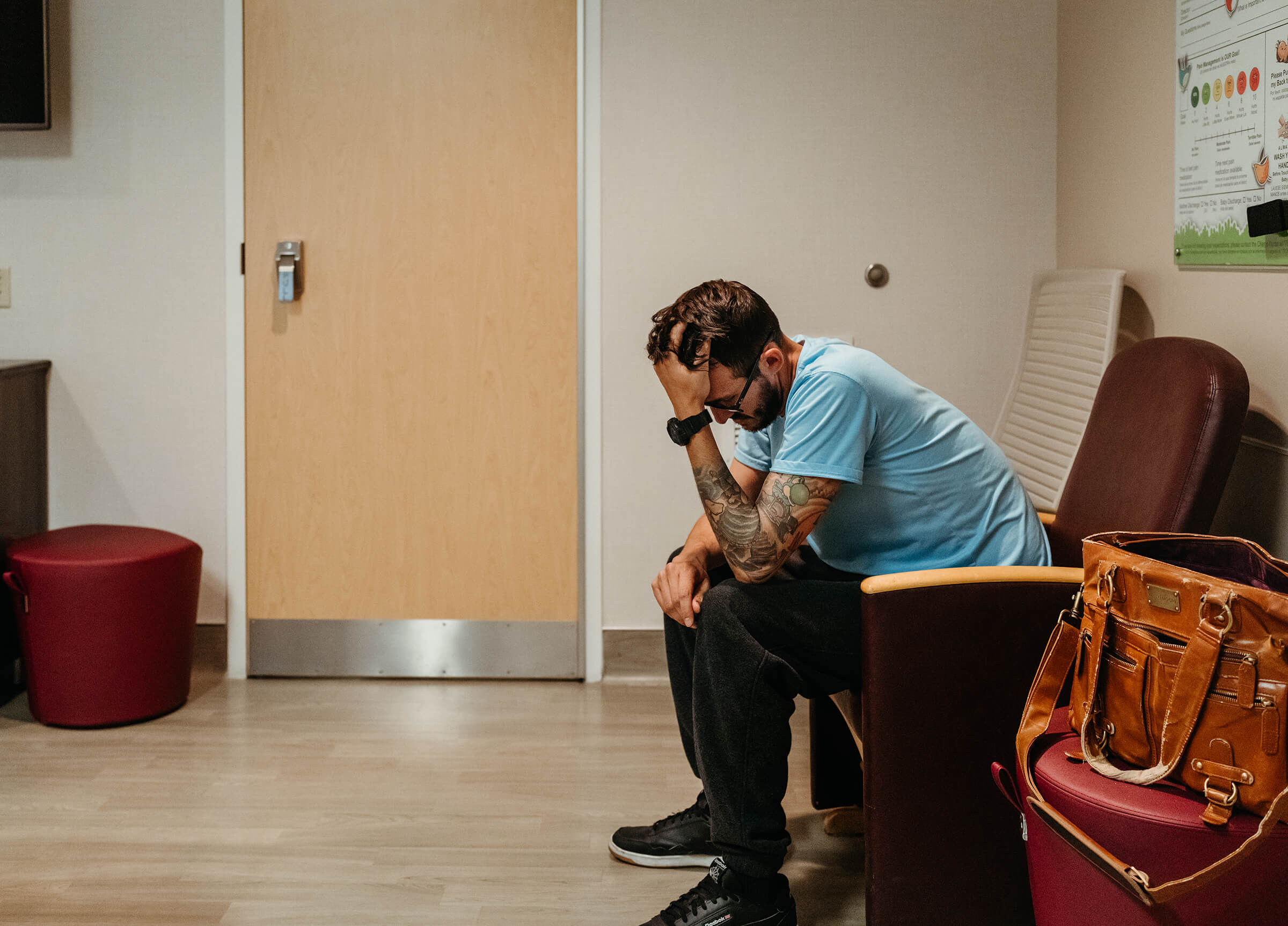 father holding his head in his hands as he worries about his partner at the hospital