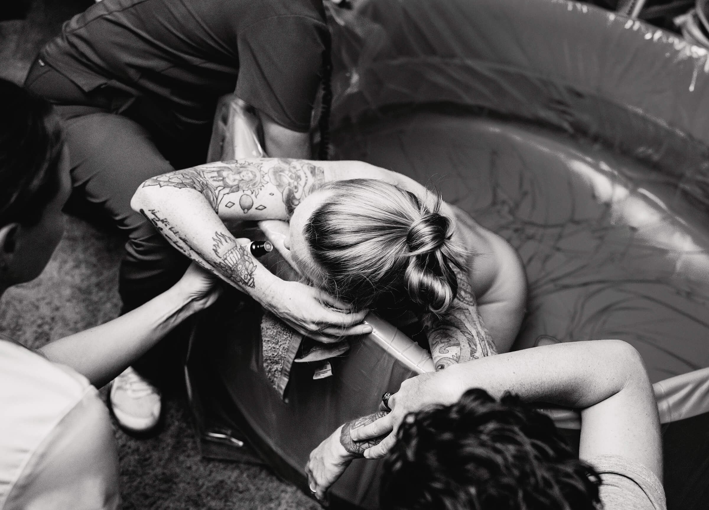 view from above as a woman leans over the edge of a birth tub while she labors