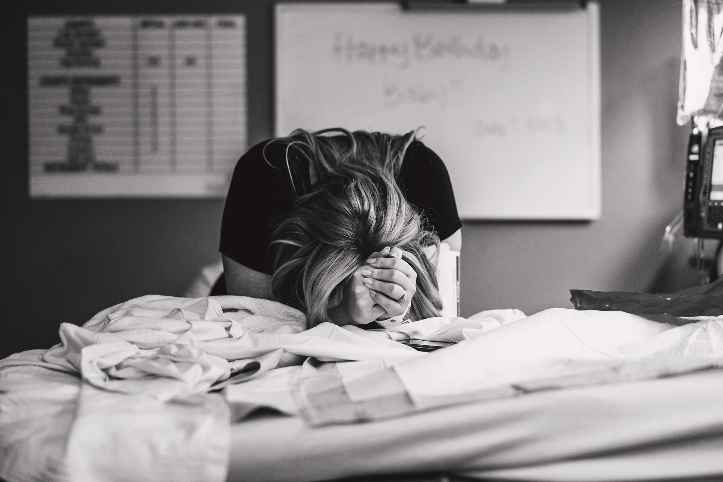 woman leaning over elevated labor bed as she breaths through contractions