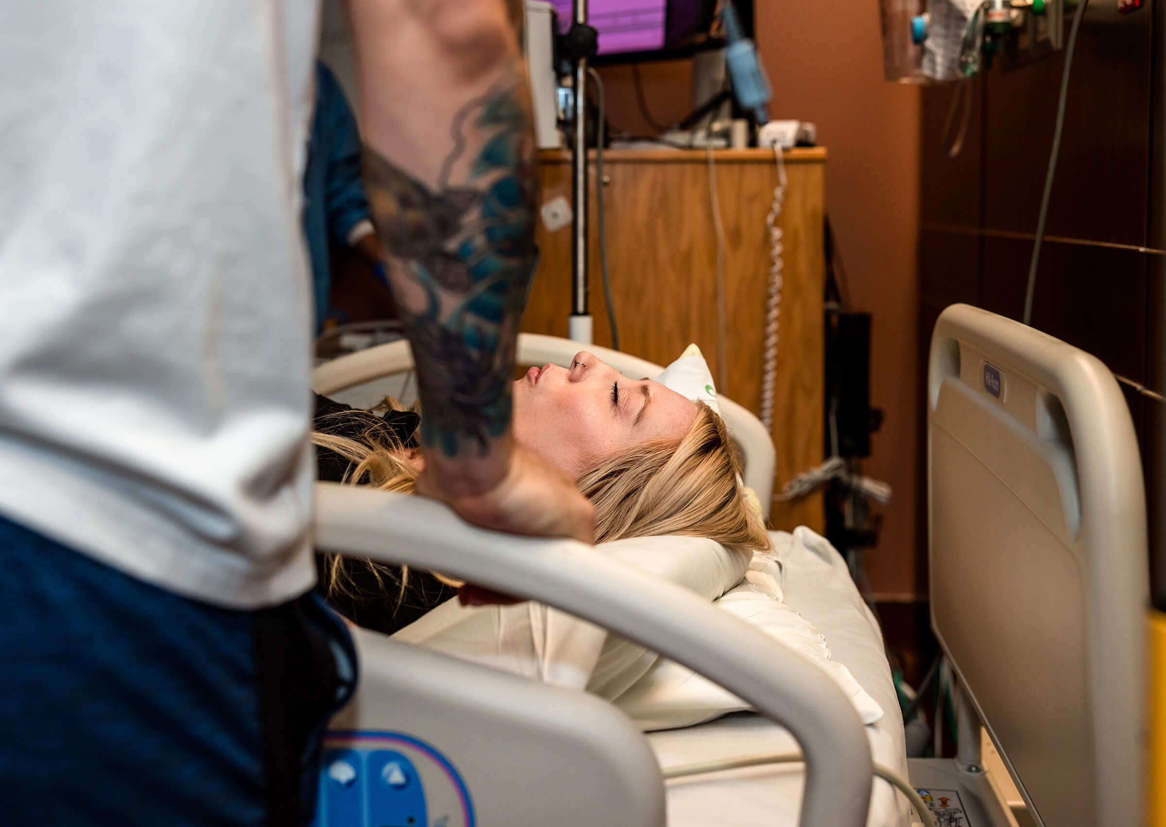 a mother lying flat on a labor bed breathing through contractions as she waits for doctor