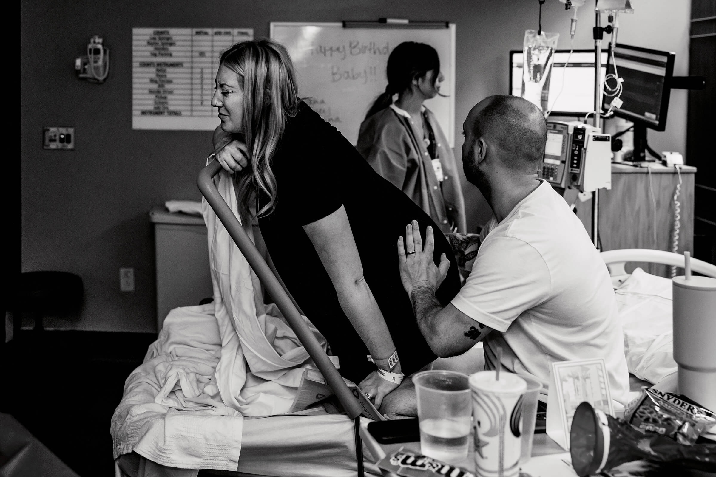 woman leaning over pushing bar on hospital bed as she breaths through a contraction