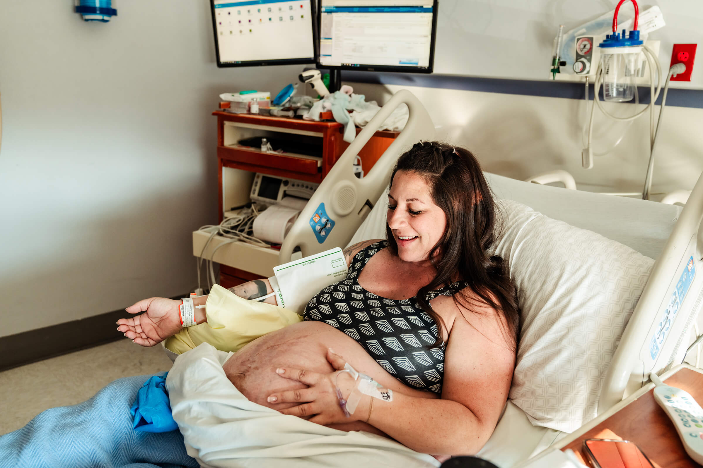 a mother pregnant with twins sitting in her hospital bed on the day of her scheduled delivery. 
