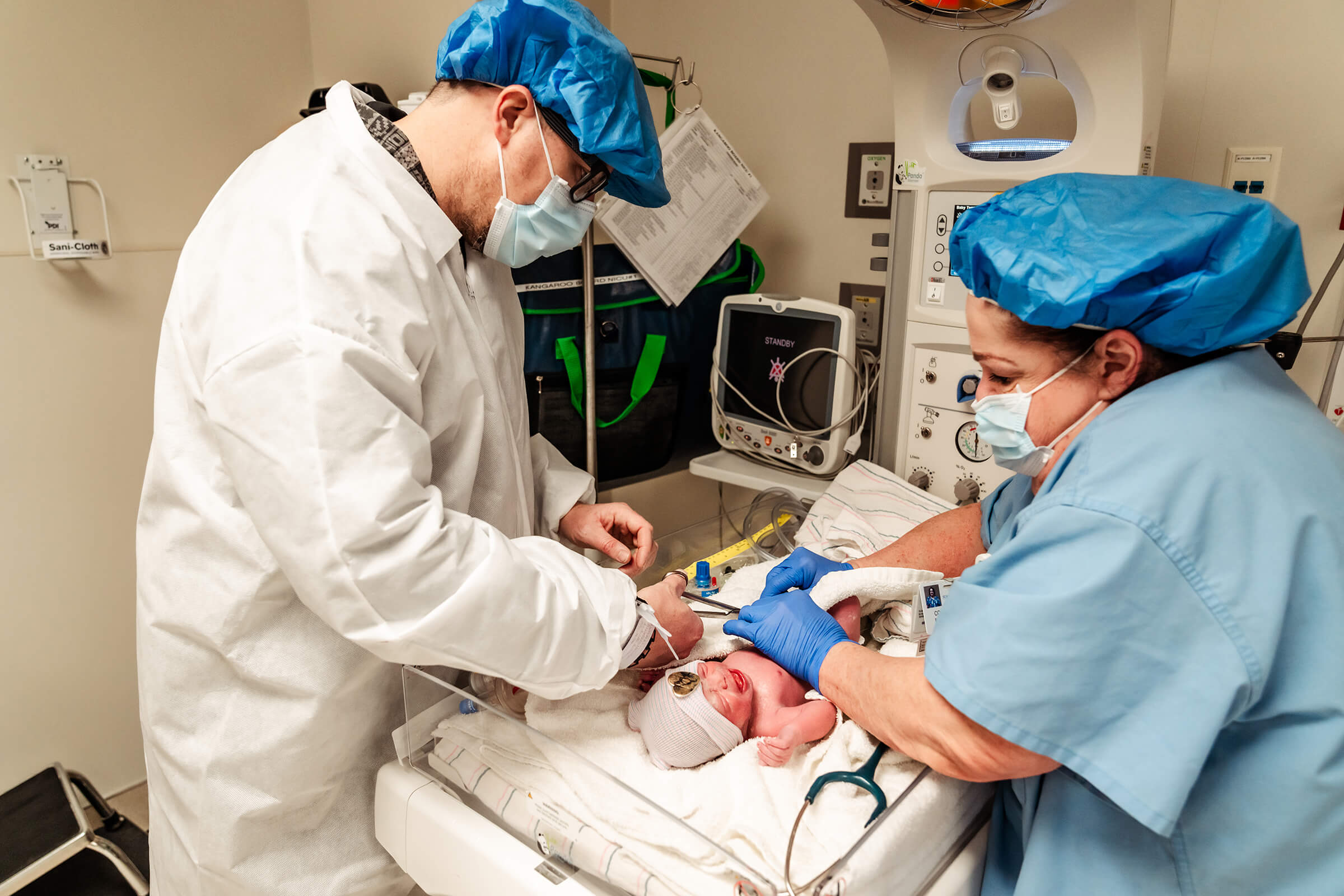 father cutting remaining cord of twin B after delivery