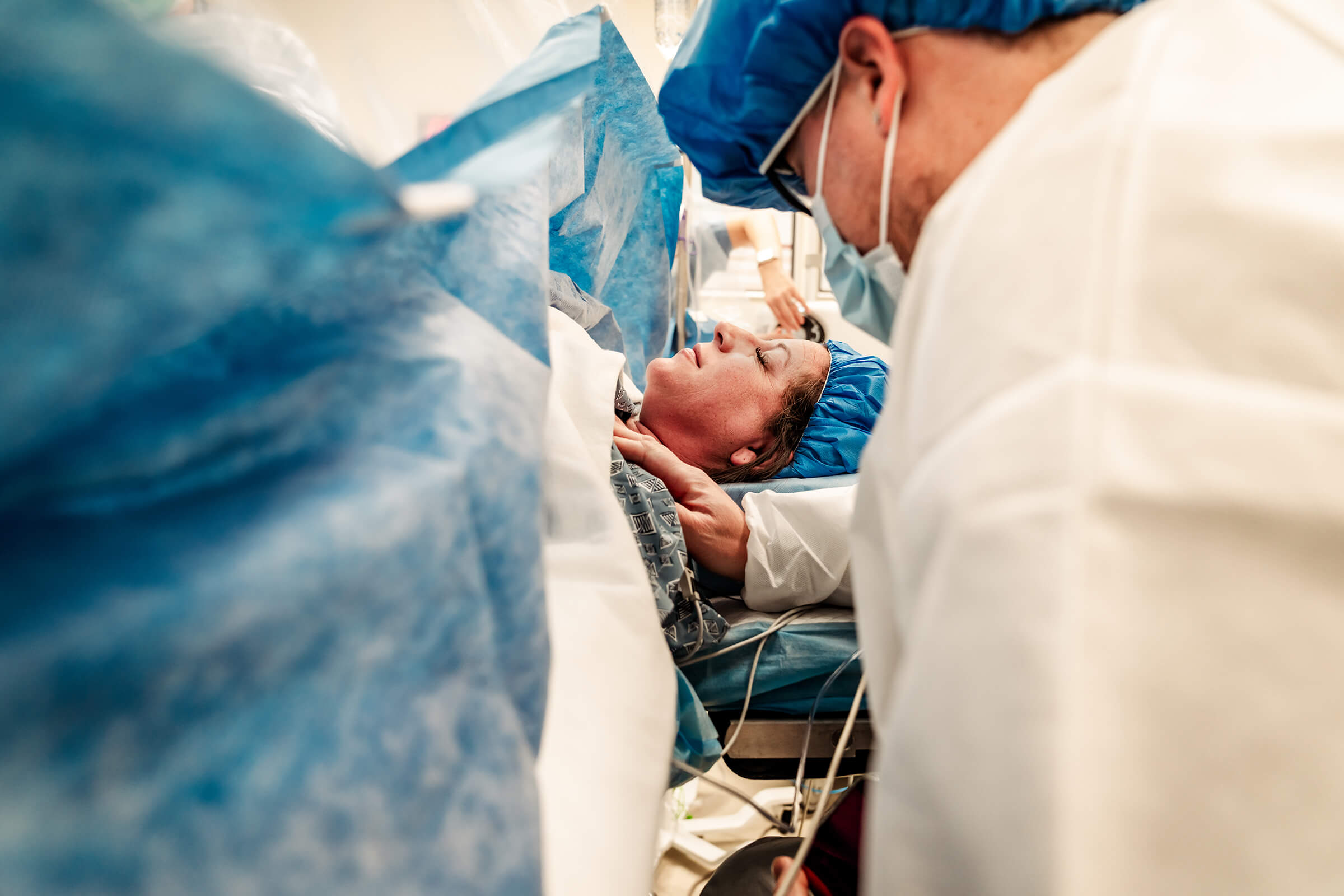 a father praying over his wife before their twins are born via cesarean