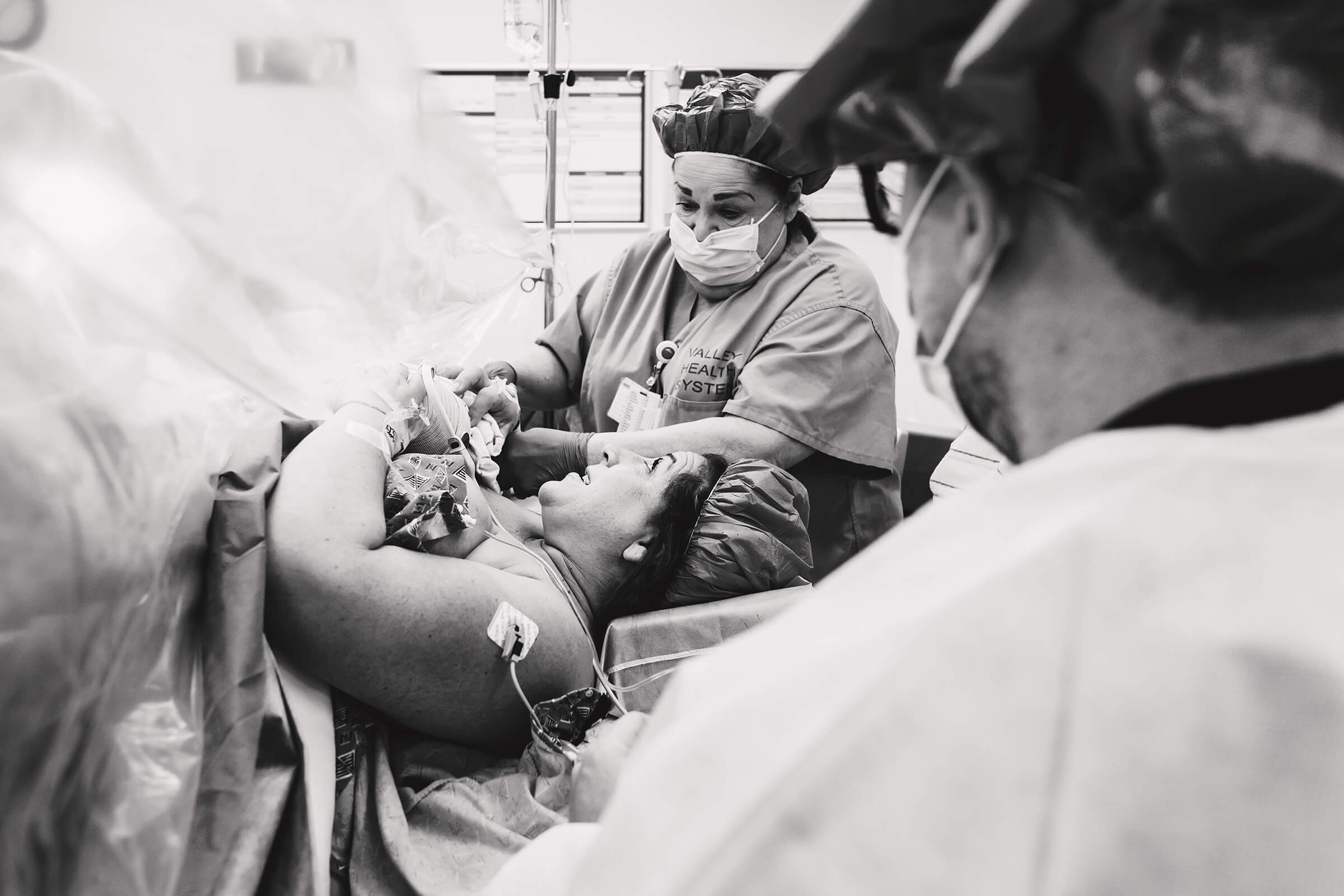nurse helping a mother hold both of her twins while she's in a cesarean delivery